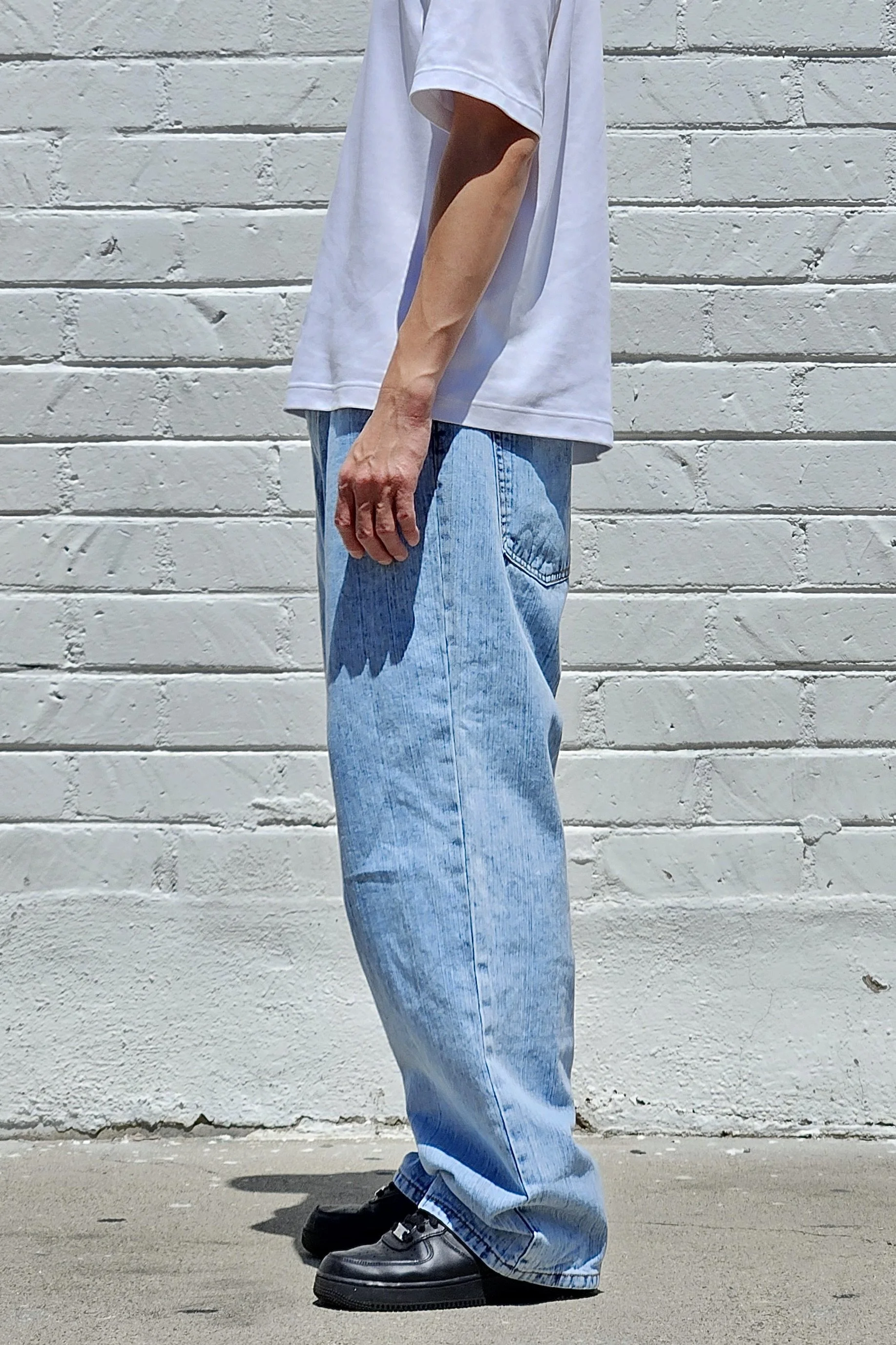 Side view of vertical pastel blue baggy jeans in slub denim.