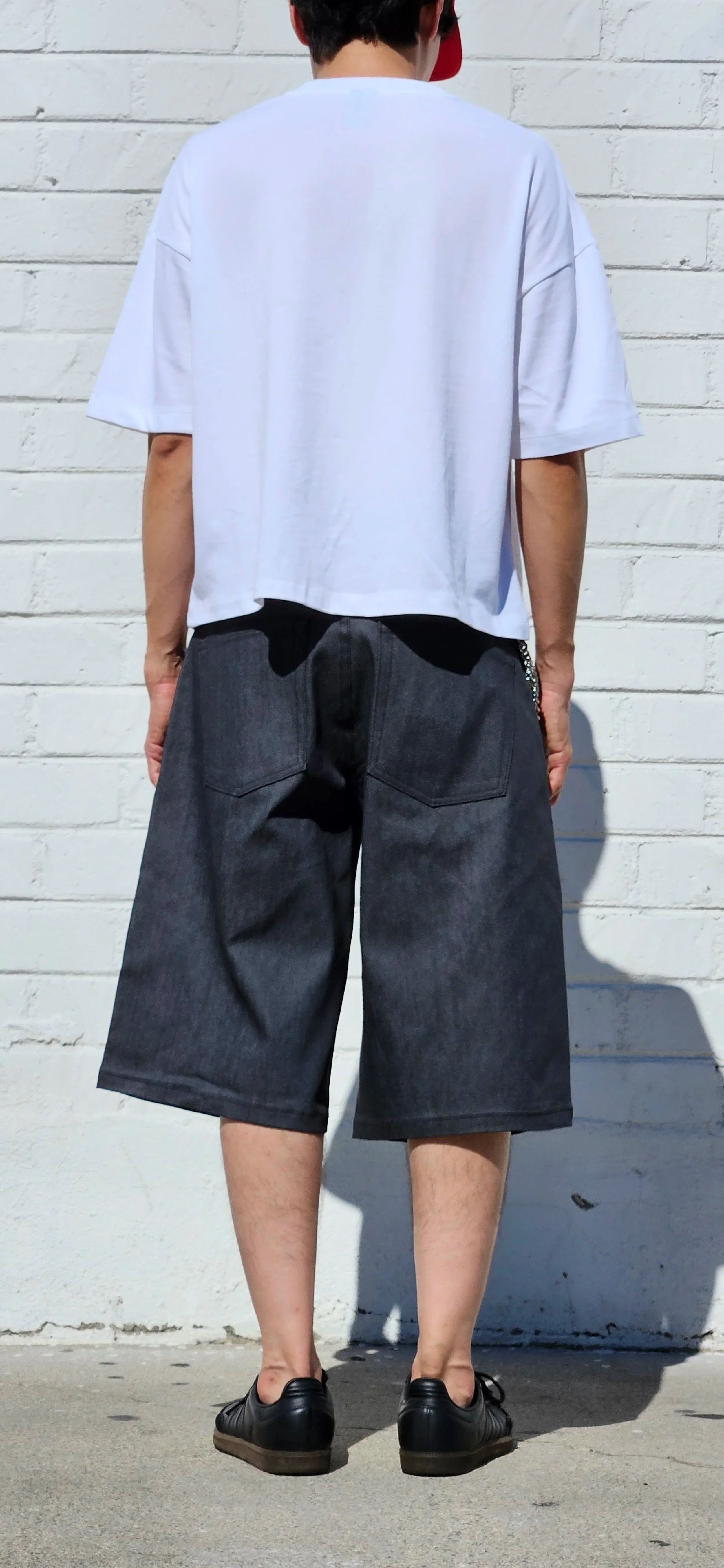 Back view of model in denim charcoal double pleated baggy jean short