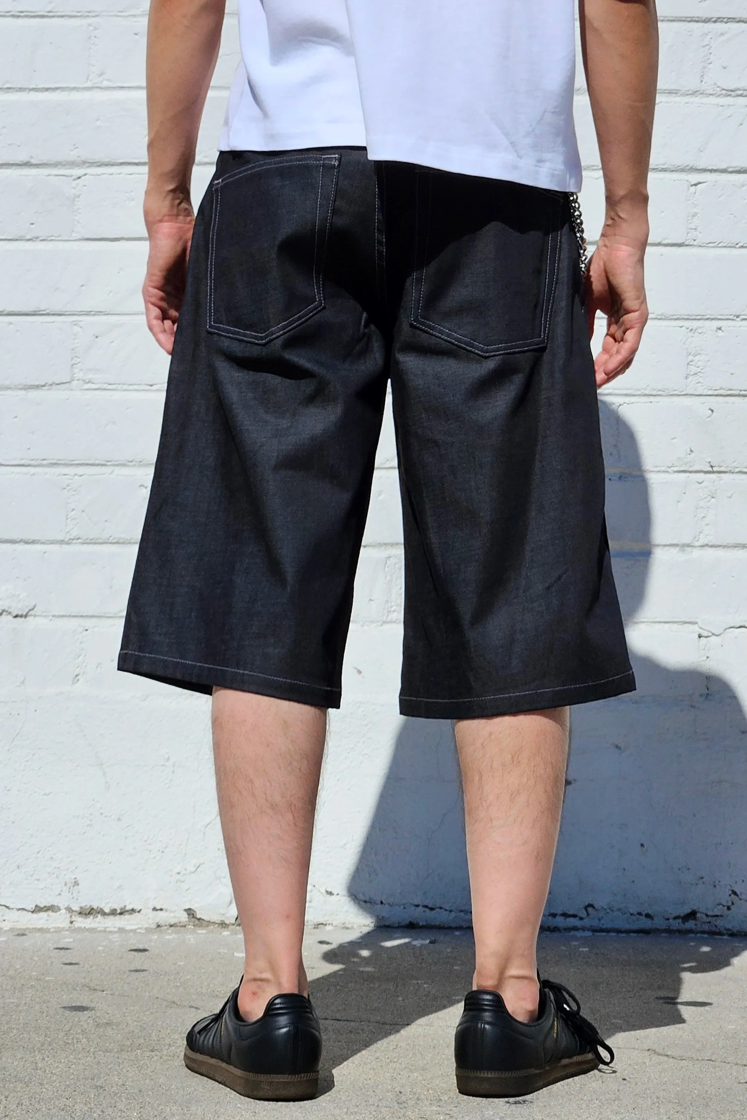 Back view of model in denim charcoal double pleated baggy jean short