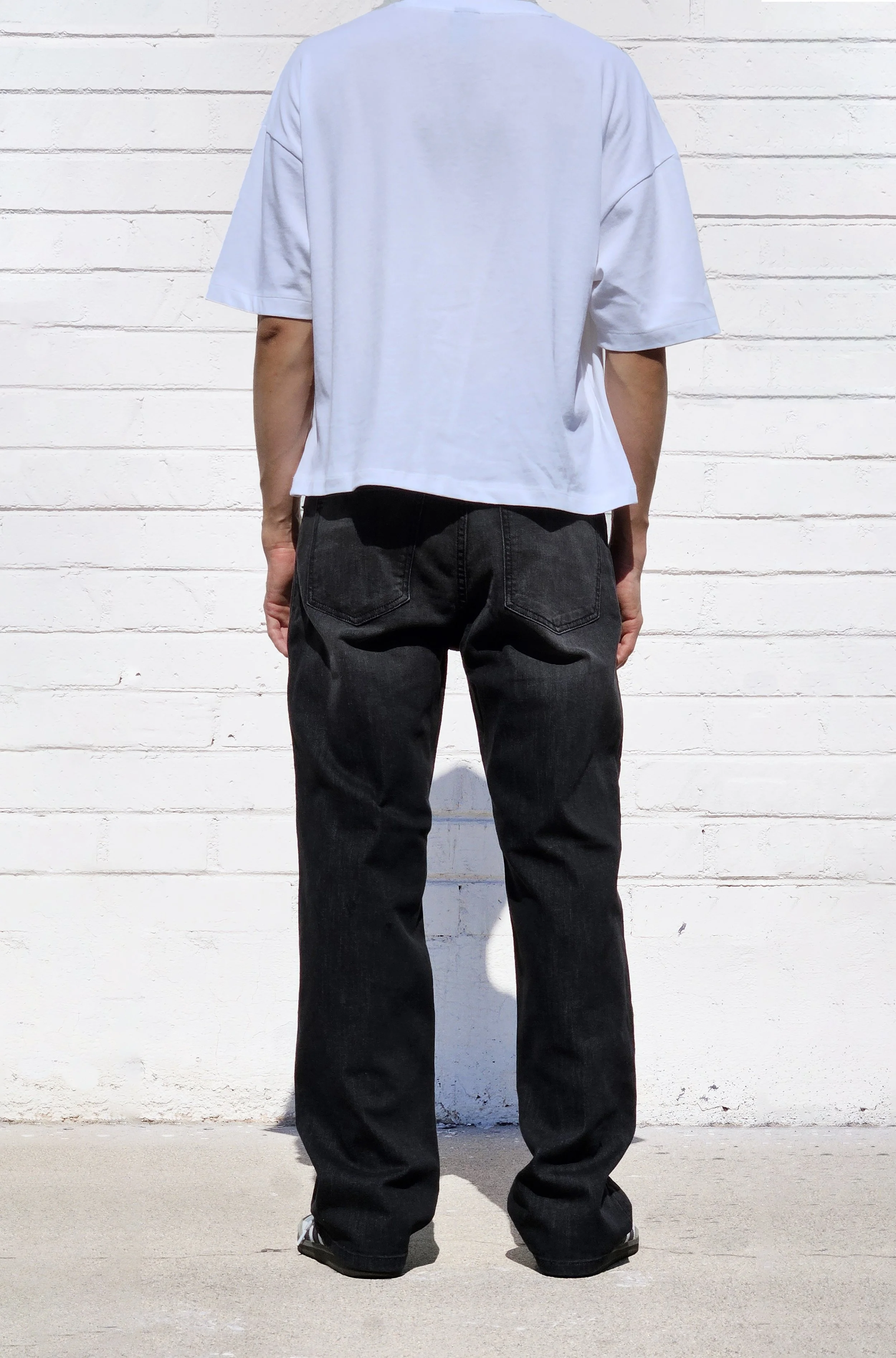 Back view of model in fade black 90s fit relaxed straight jeans.