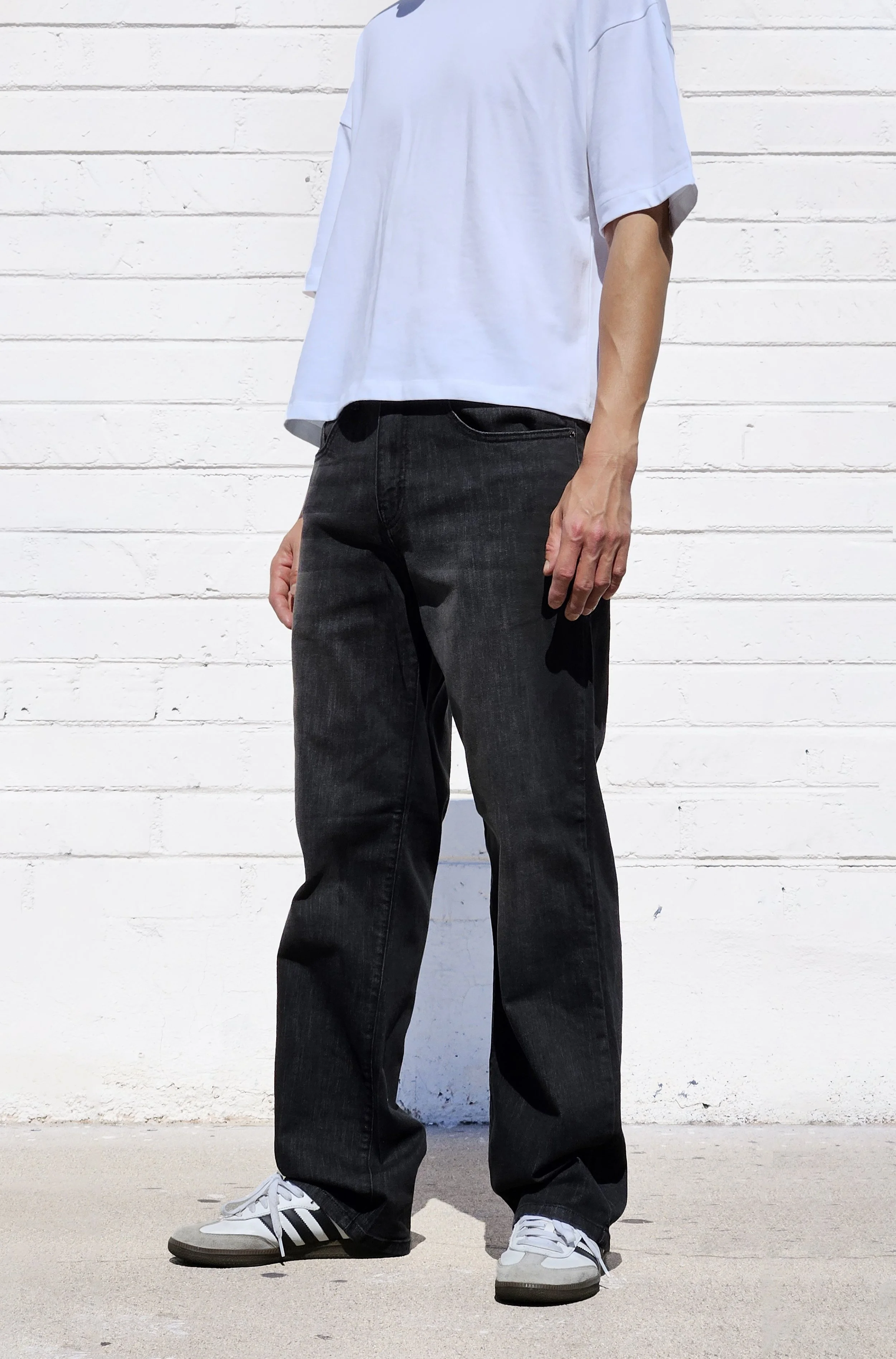 Side view of model in fade black 90s fit relaxed straight jeans.