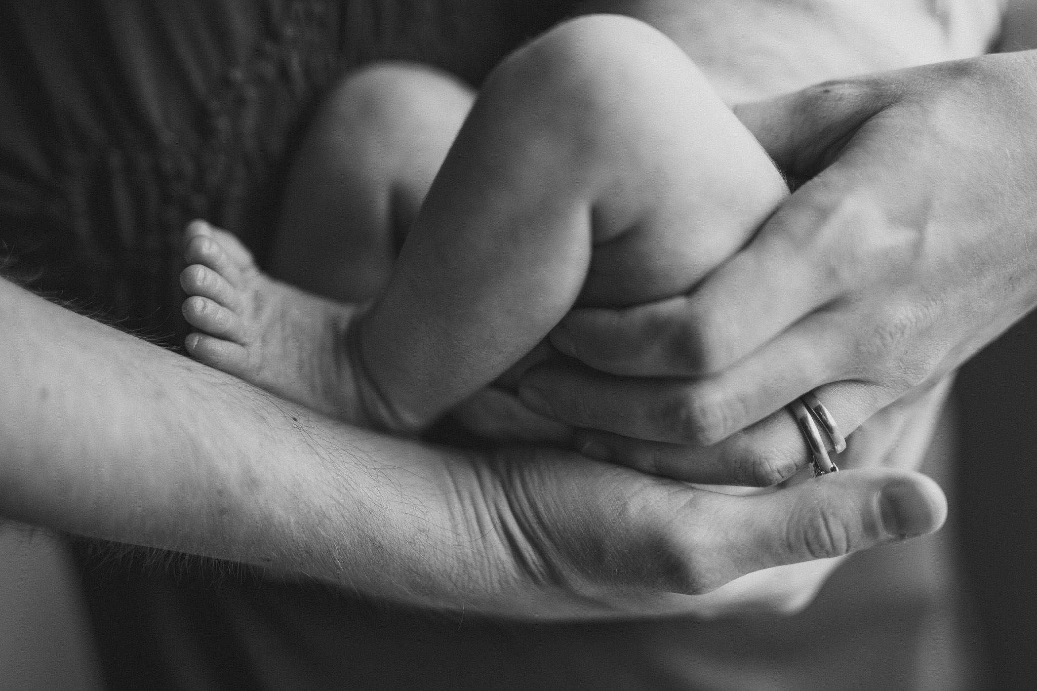 thomas wywrot photography nashville newborn photographer closeup mother holding baby wedding rings infant feet