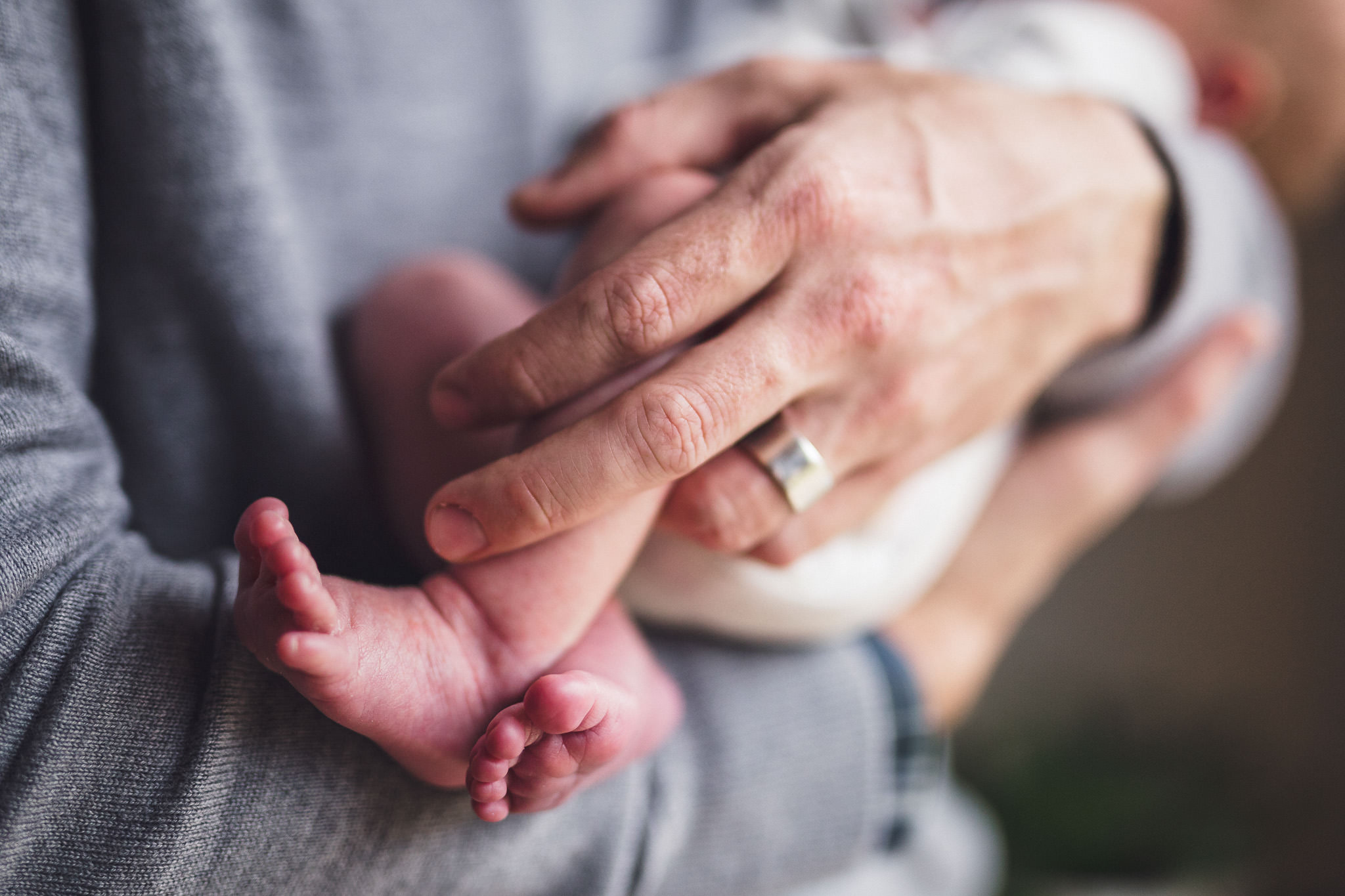 thomas wywrot photography nashville newborn photographer closeup of father holding two week old baby wedding ring crossed infant feet