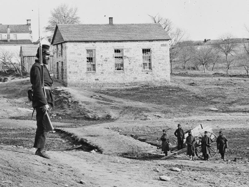 March, 1862. This sentry is wearing dark blue trousers shortened by cutting off the cuffs, and the other five men also appear to be wearing dark blues. (LOC#: LC-B811-302)