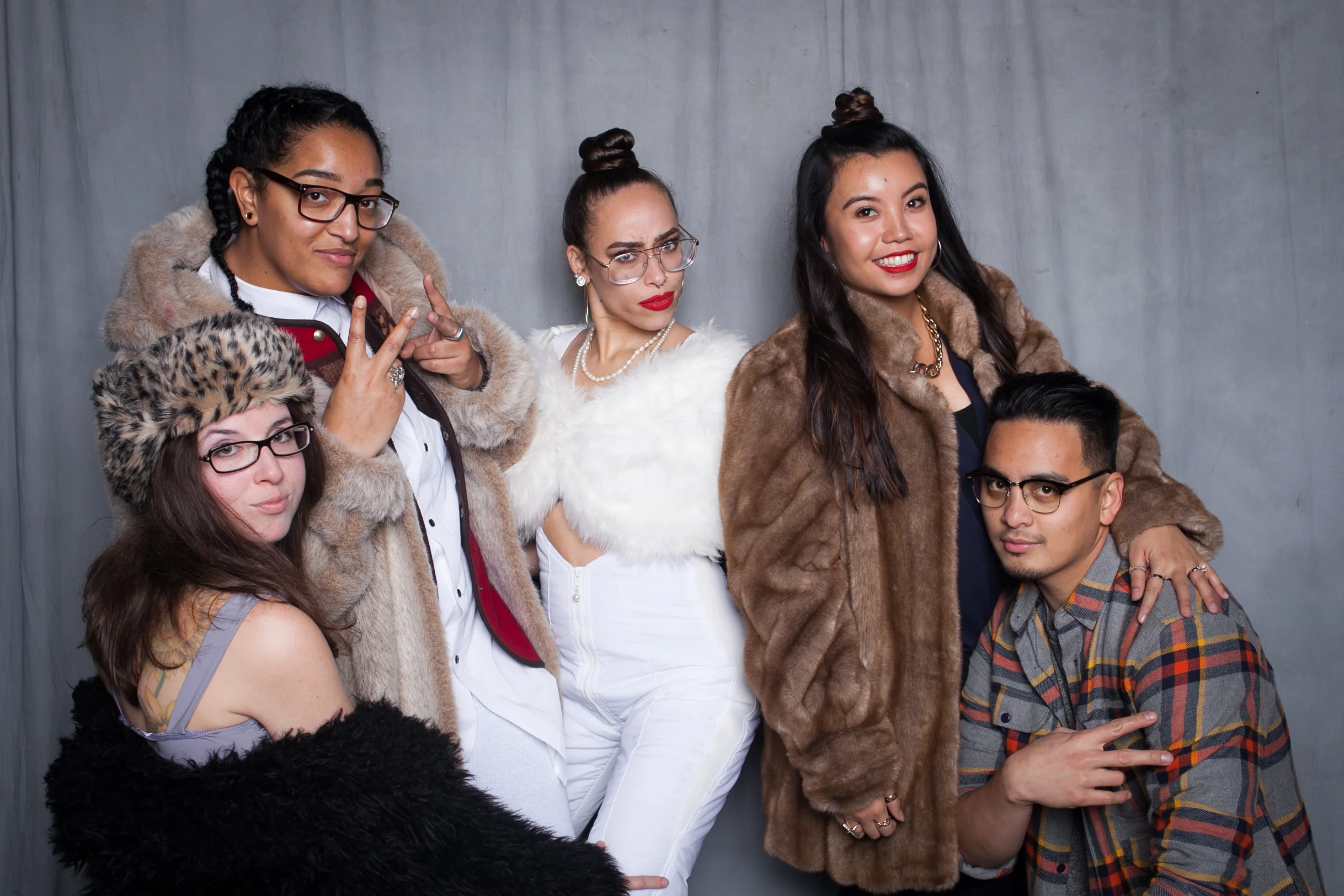 A group of friends posing in fur coats and glasses in front of a gray fabric backdrop for the 3-hour Photo Lounge Plus package in Portland.