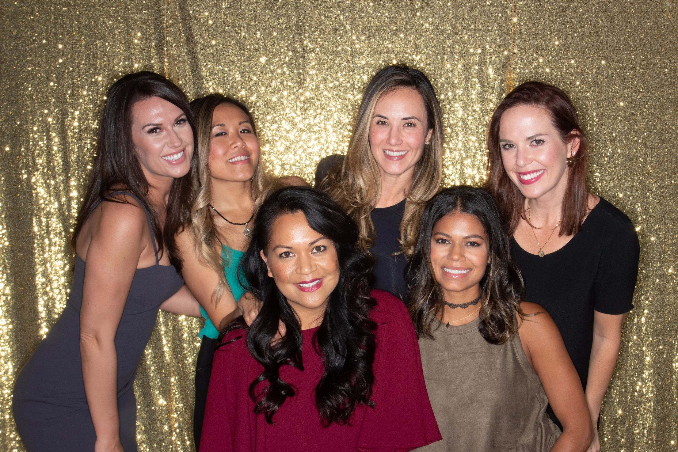 A group of colleagues posing in front of a gold sequin backdrop for the Corporate Party Box photo booth package in Portland.
