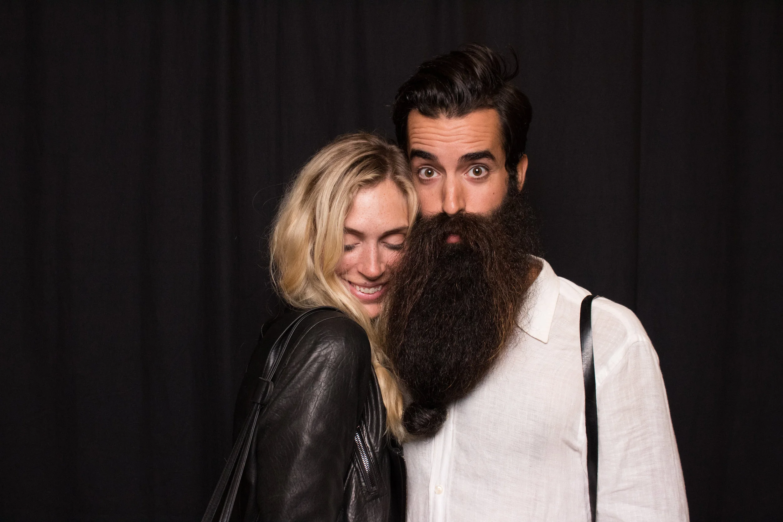 Man with large beard poses with beautiful woman in the mirror me photo booth in Portland Oregon