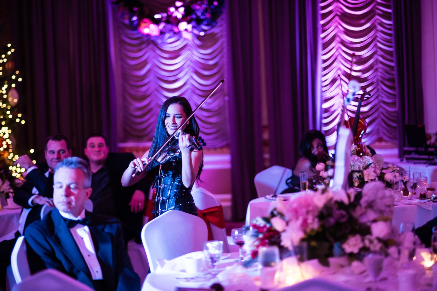 Female violinist performing live on stage under purple ambient lighting at a Portland corporate gala.