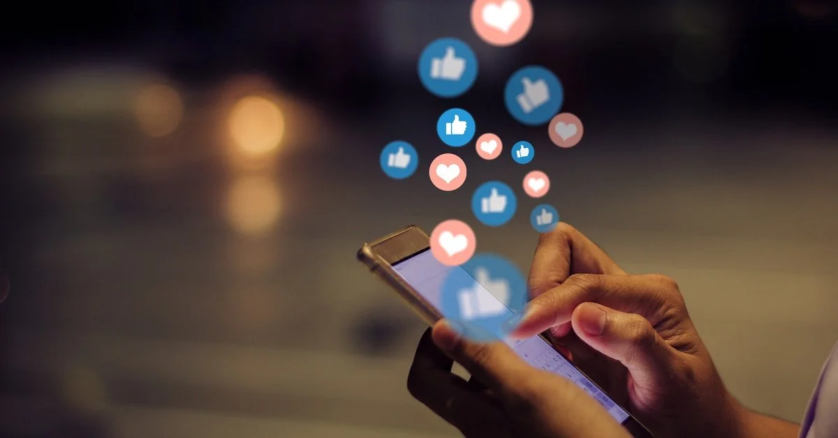 A close-up of someone holding their smartphone after an event. There are social media interaction emojis above the phone.