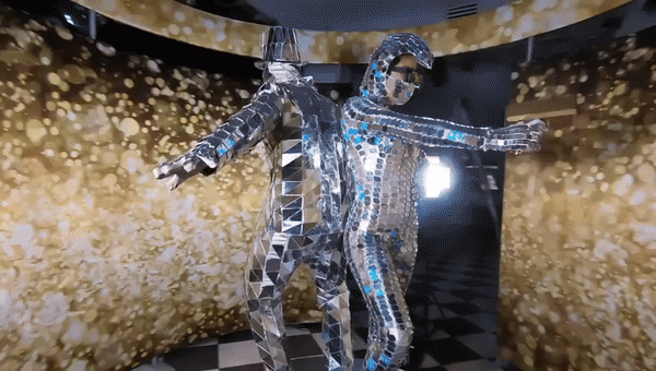 Performers in reflective mirror suits posing on a 360 video platform in front of a gold sequin backdrop for the Deluxe 360 Photo Booth package.