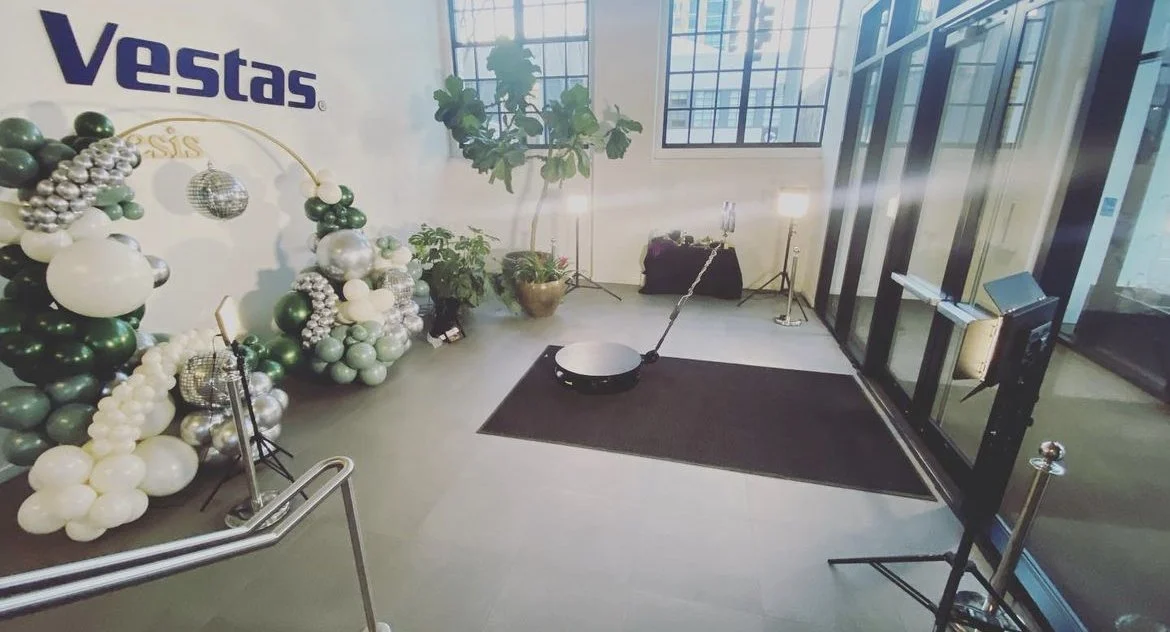 Full corporate event setup for the 3-hour 360 Photo Booth Plus package featuring custom green balloon arch decor.