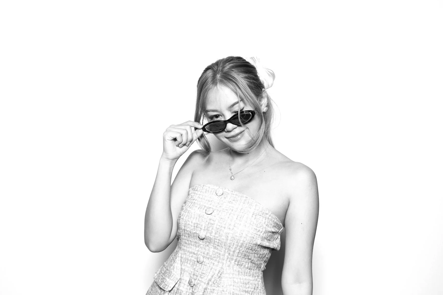 Black and white editorial-style portrait of a woman lowering her sunglasses at the Glam Booth in Portland