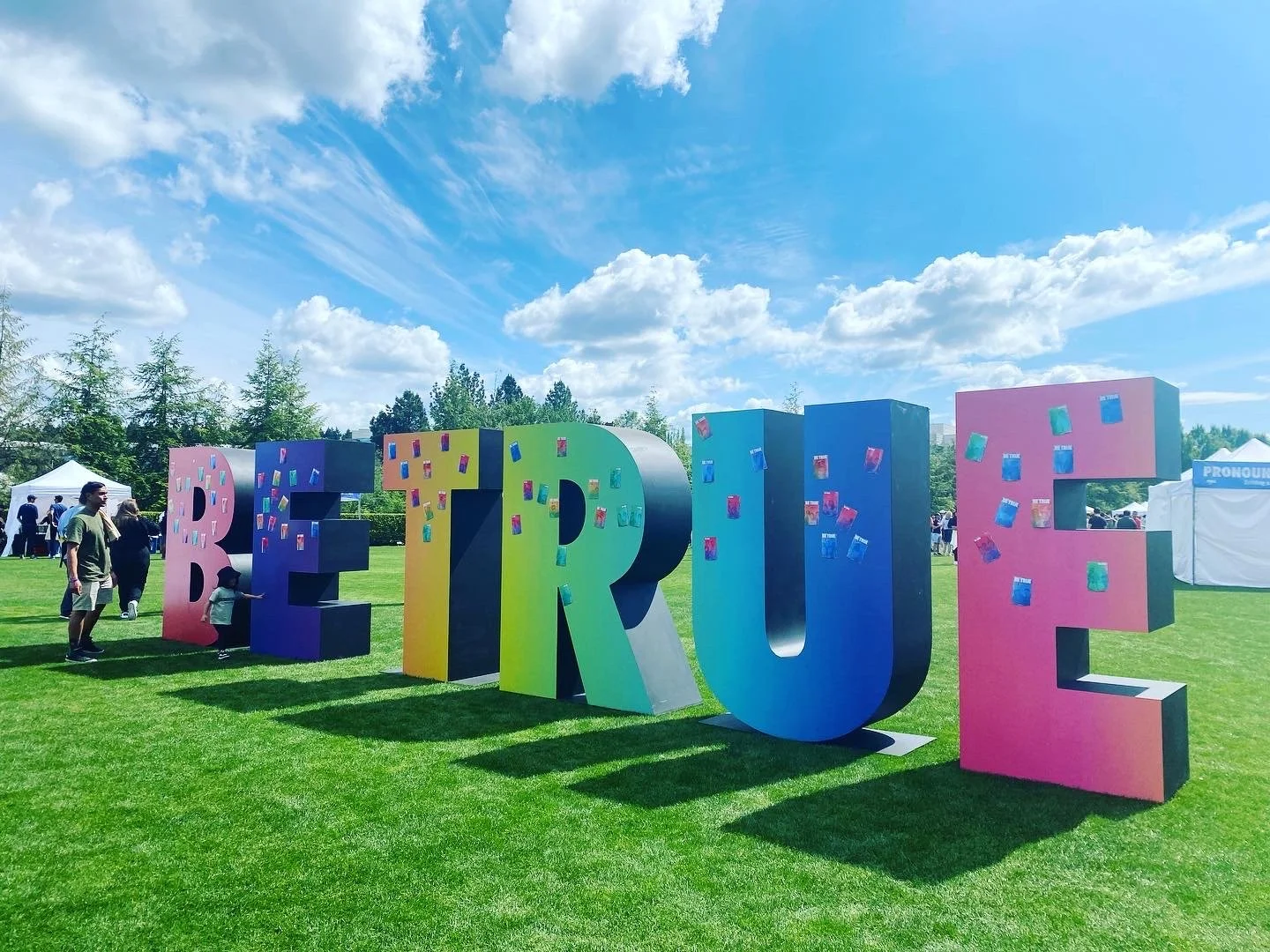 Large colorful BE TRUE block letter display at an outdoor branded event activation in Portland.