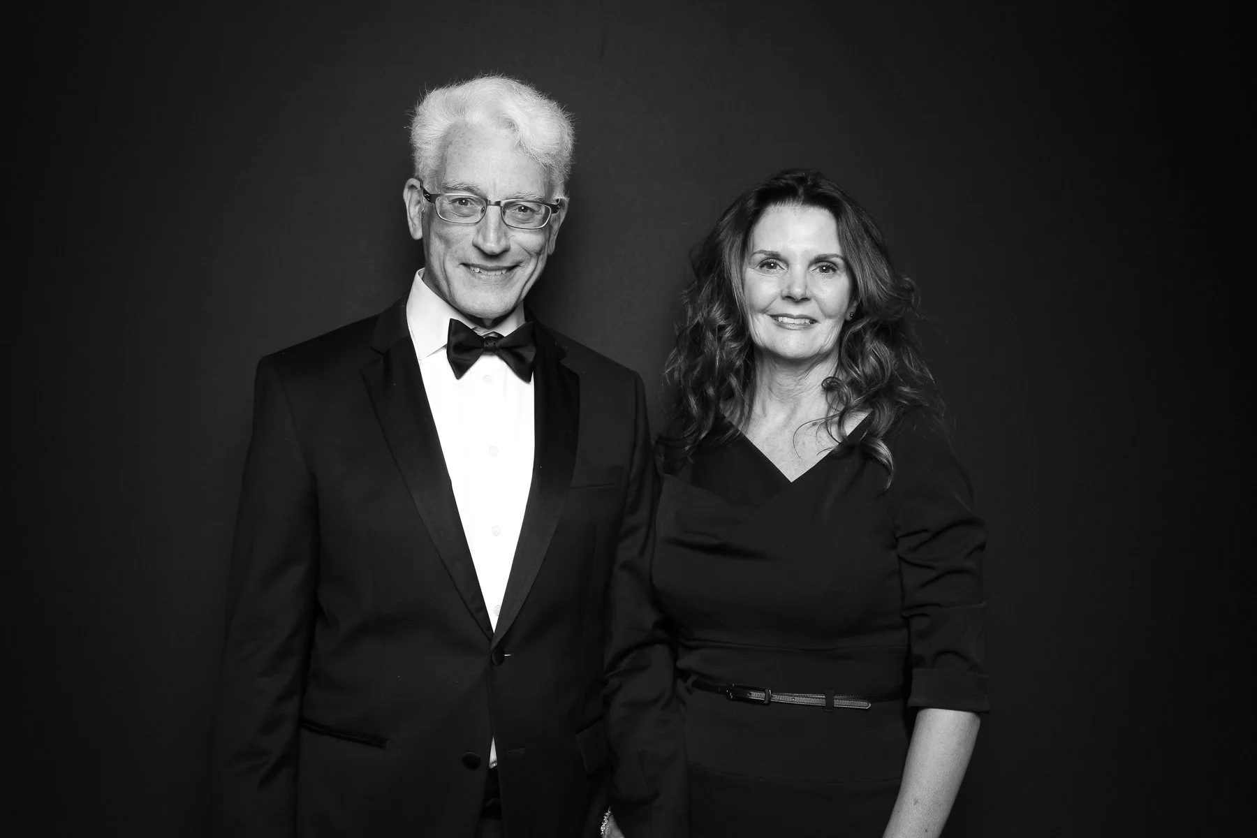 Man with bow tie poses with wife in a beautiful reverse glam photo booth portrait