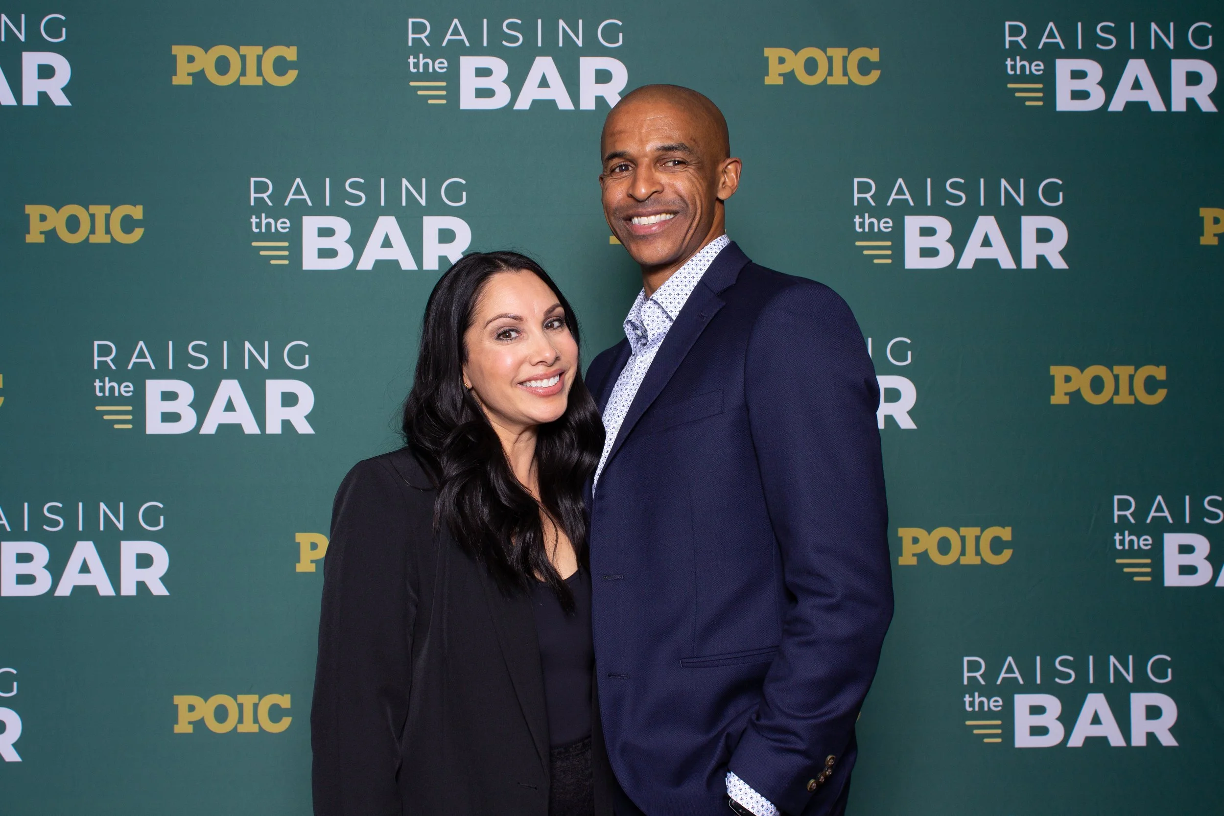 Guests posing in front of a custom branded step-and-repeat backdrop at a corporate event