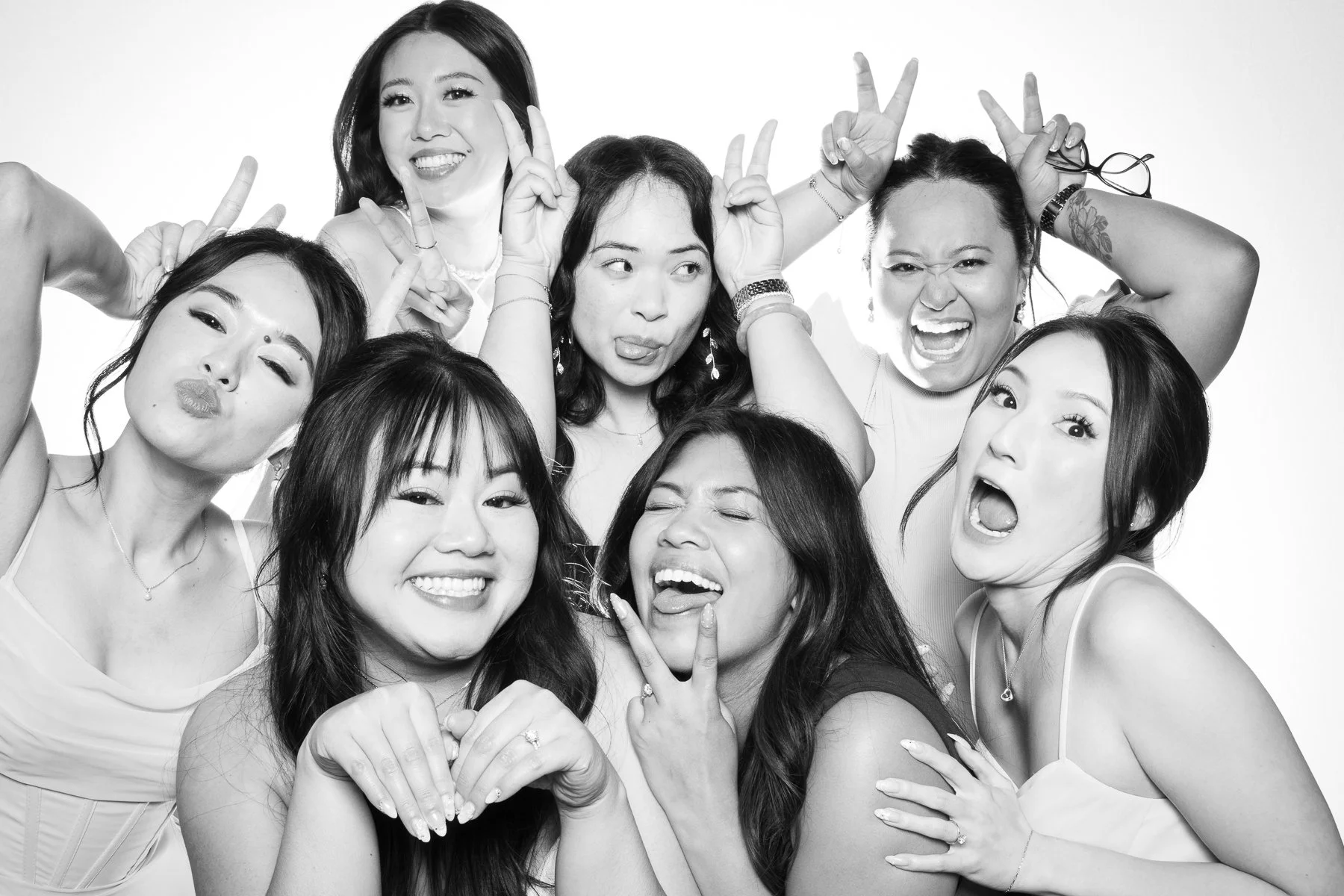 Black and white group portrait of women posing playfully at the Glam Booth photo experience