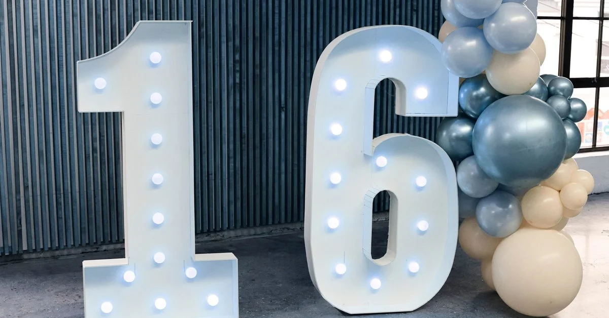 A pair of light boxes in the shape of 16. The boxes are white with bulb lights in the center, next to round balloons.
