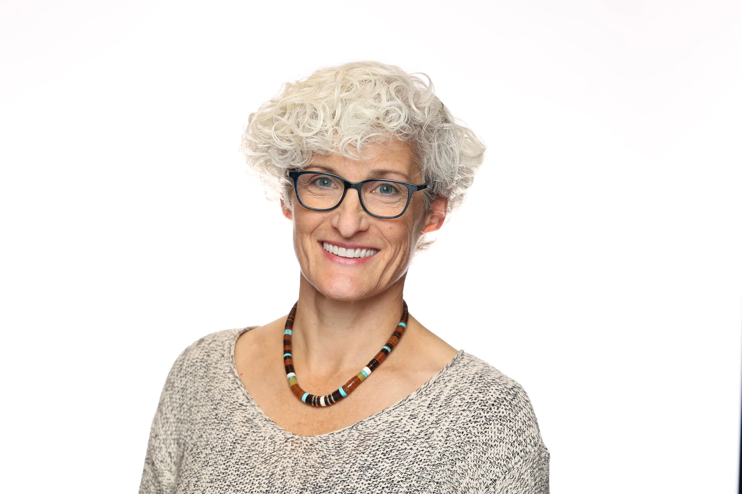 Woman smiles in a corporate headshot photo with a white background