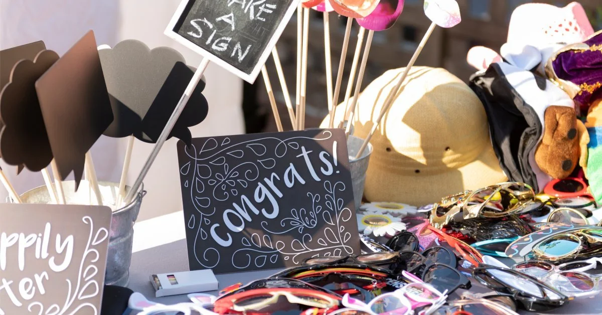 A photo booth rental prop table at a wedding reception full of props, including masks, signs, hats, and sunglasses.