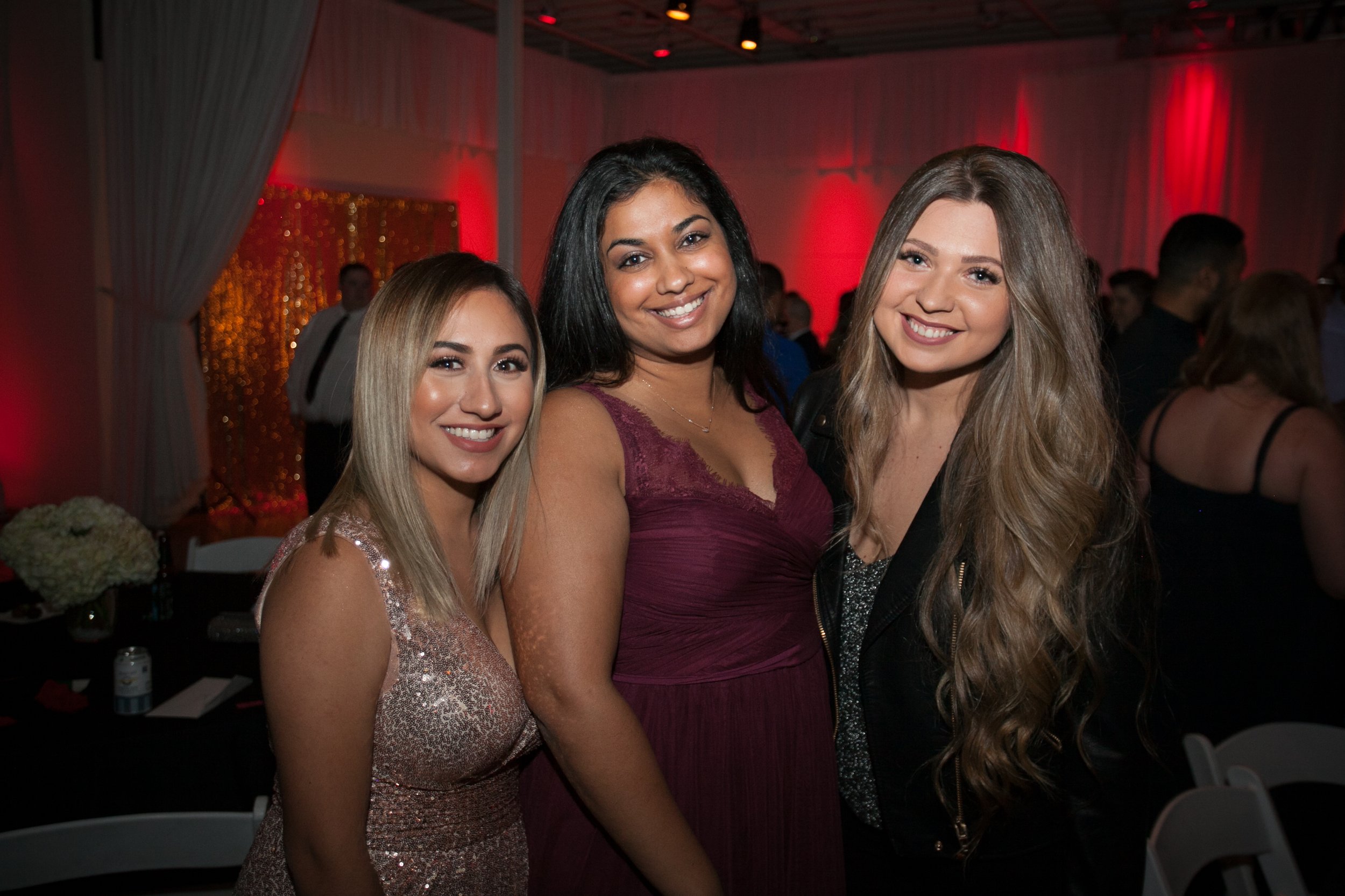 Three women in formal evening wear posing for a candid photo during a corporate event in Portland.