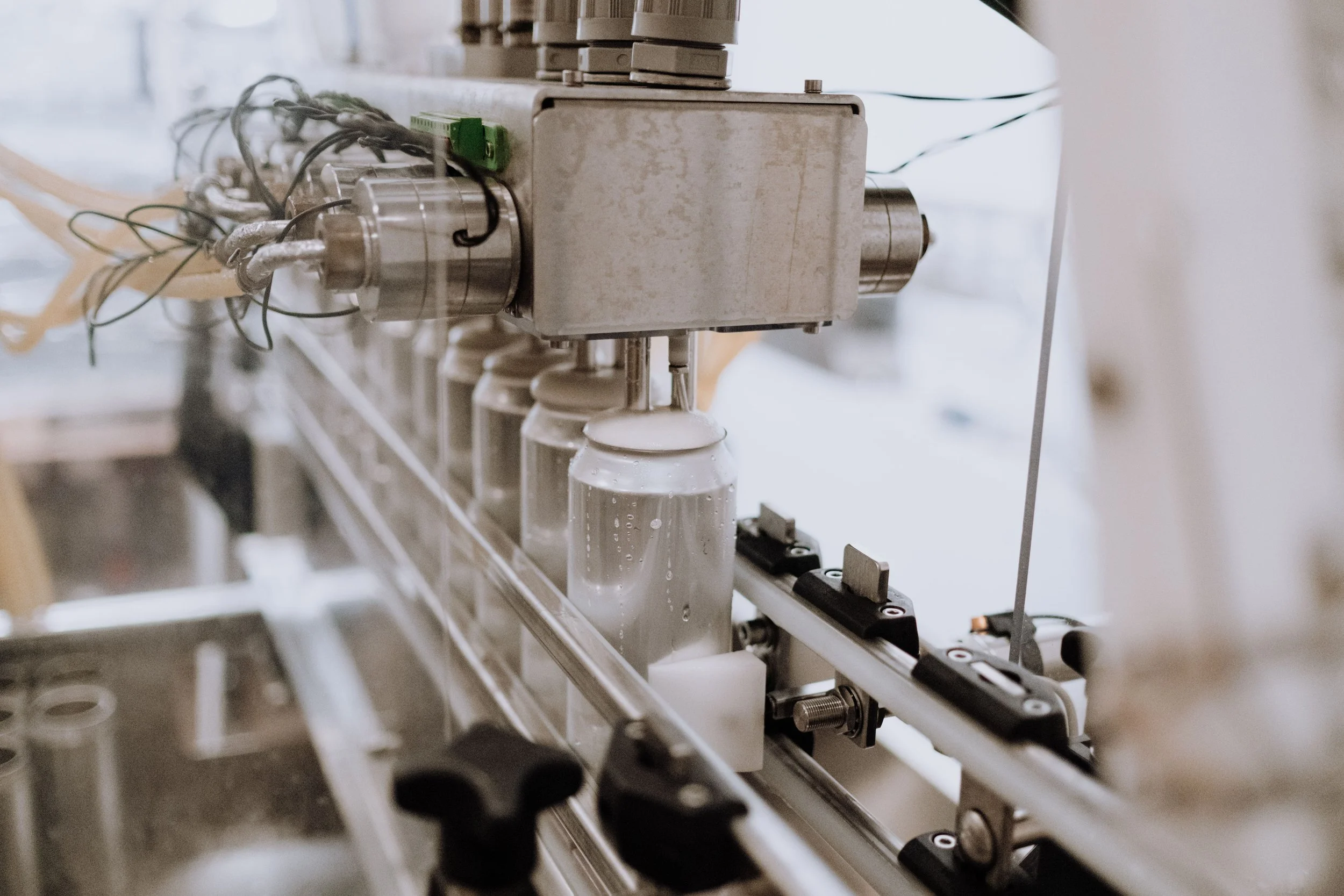 Close-up view of machinery with glass vials and various mechanical parts, likely part of a pharmaceutical or manufacturing process.