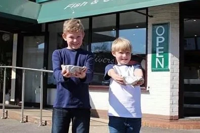 Ollie Webb (L) and Edward Walton (R) ask for more chips at Oliver’s Chip Shop in Old Basing