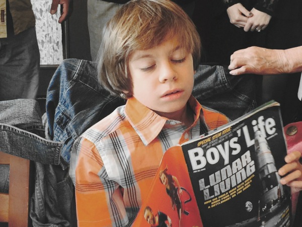 Dylan Lopez, the son of Sandra's cousins Joe and Sara and grandson of Aunt Margaret Lopez, endures the family reunion by reading a good story. Photo ©2015 Sandra Cisneros