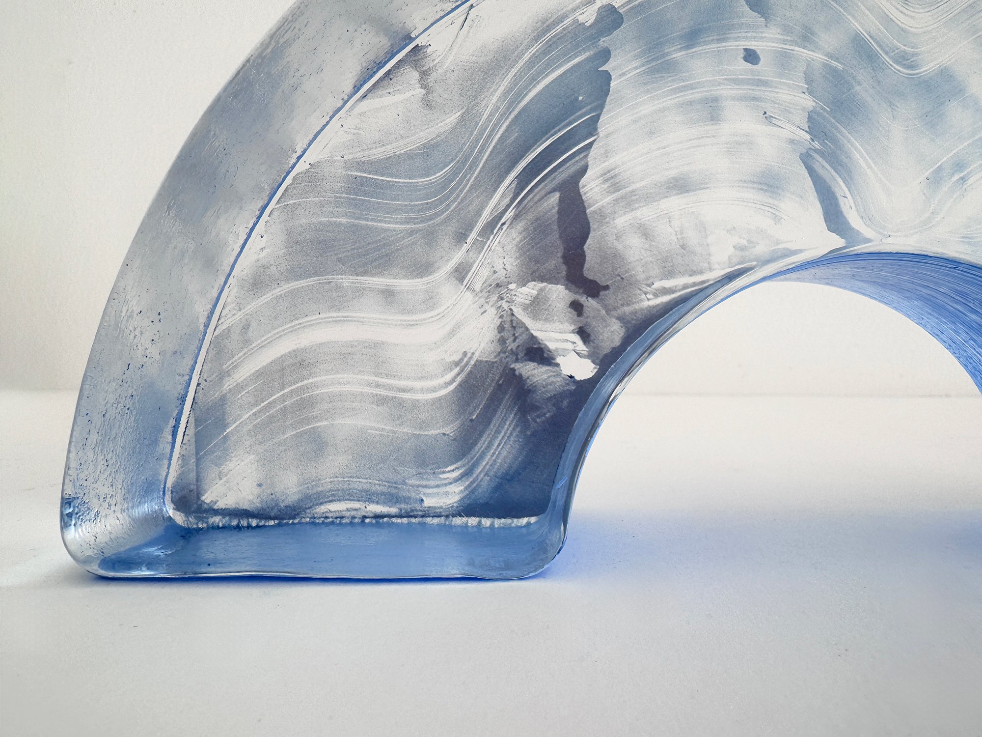 Detail of flowing white markings across the pale blue glass of Lisette Schumacher’s Spatial Shade Arch I.