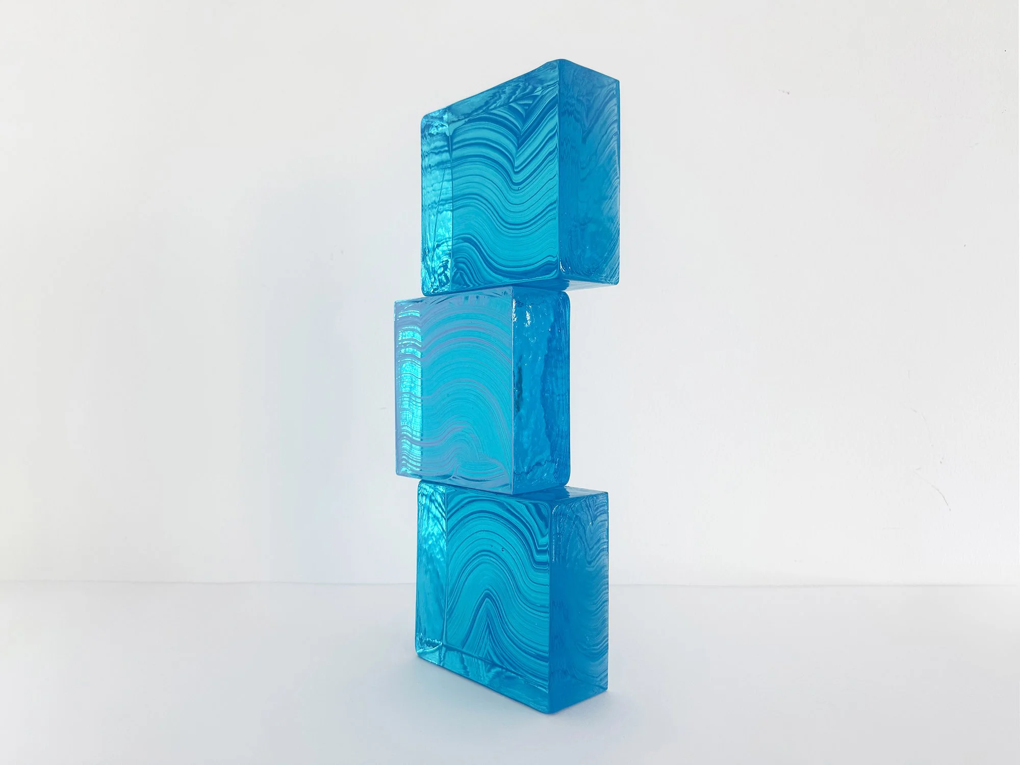 Architectural glass artwork with vertical stacked composition and translucent blue surfaces