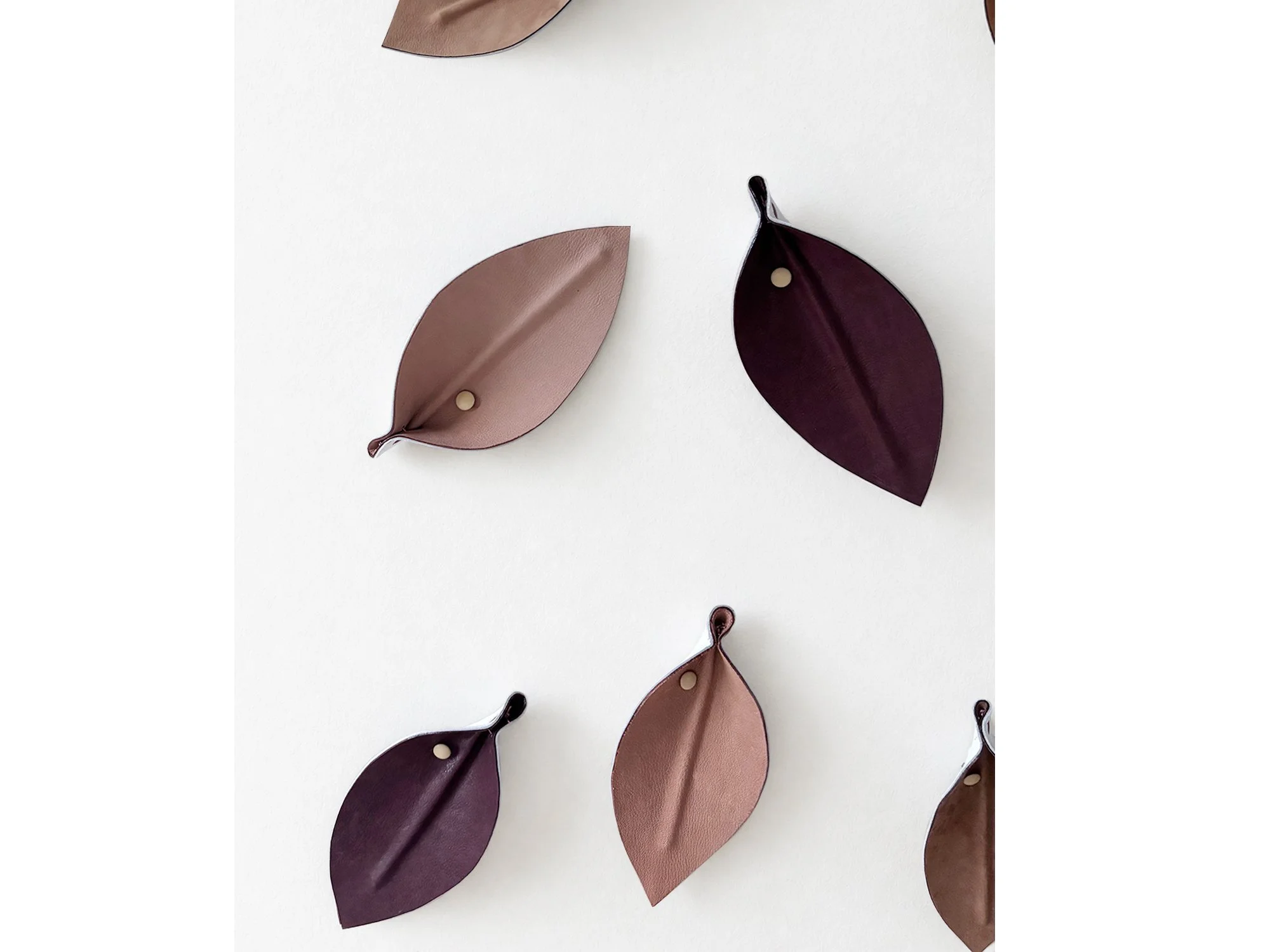 Close-up of Madelon Uljee’s Leaves Neutrals, showing the folded leather leaf forms, raised central veins and small brass-toned fasteners.