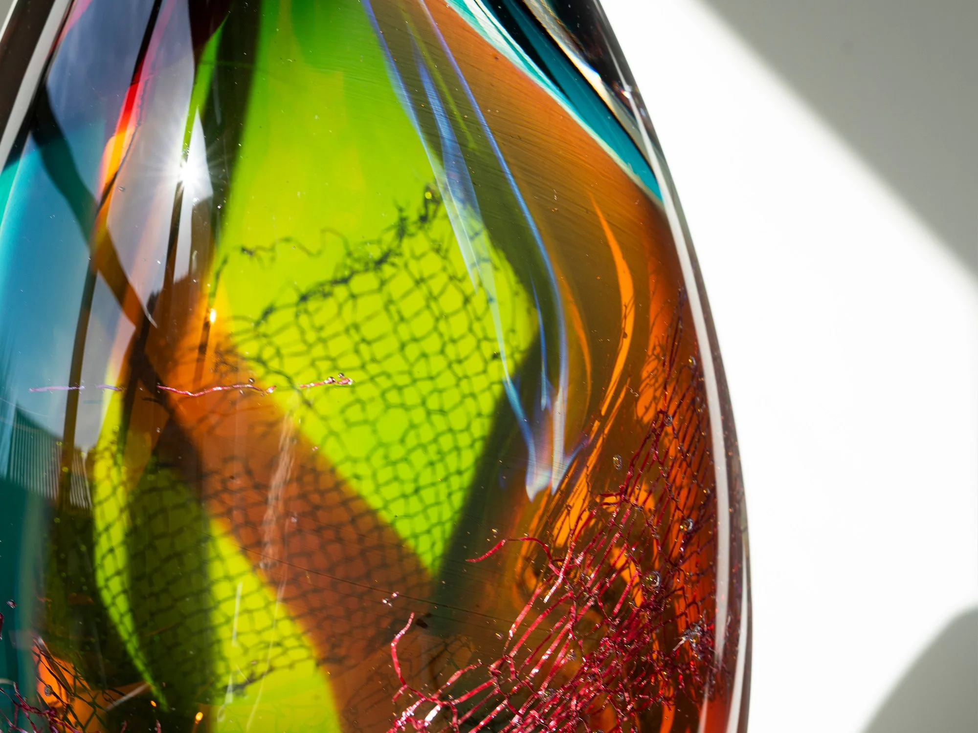Detail of turquoise, green, amber and red layers in a blown glass sculpture by Francisca Snel