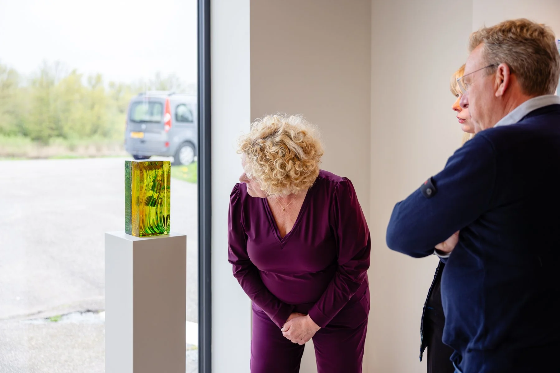 Visitors viewing a glass sculpture by Lisette Schumacher at Root Gallery during the Where Light Lands exhibition