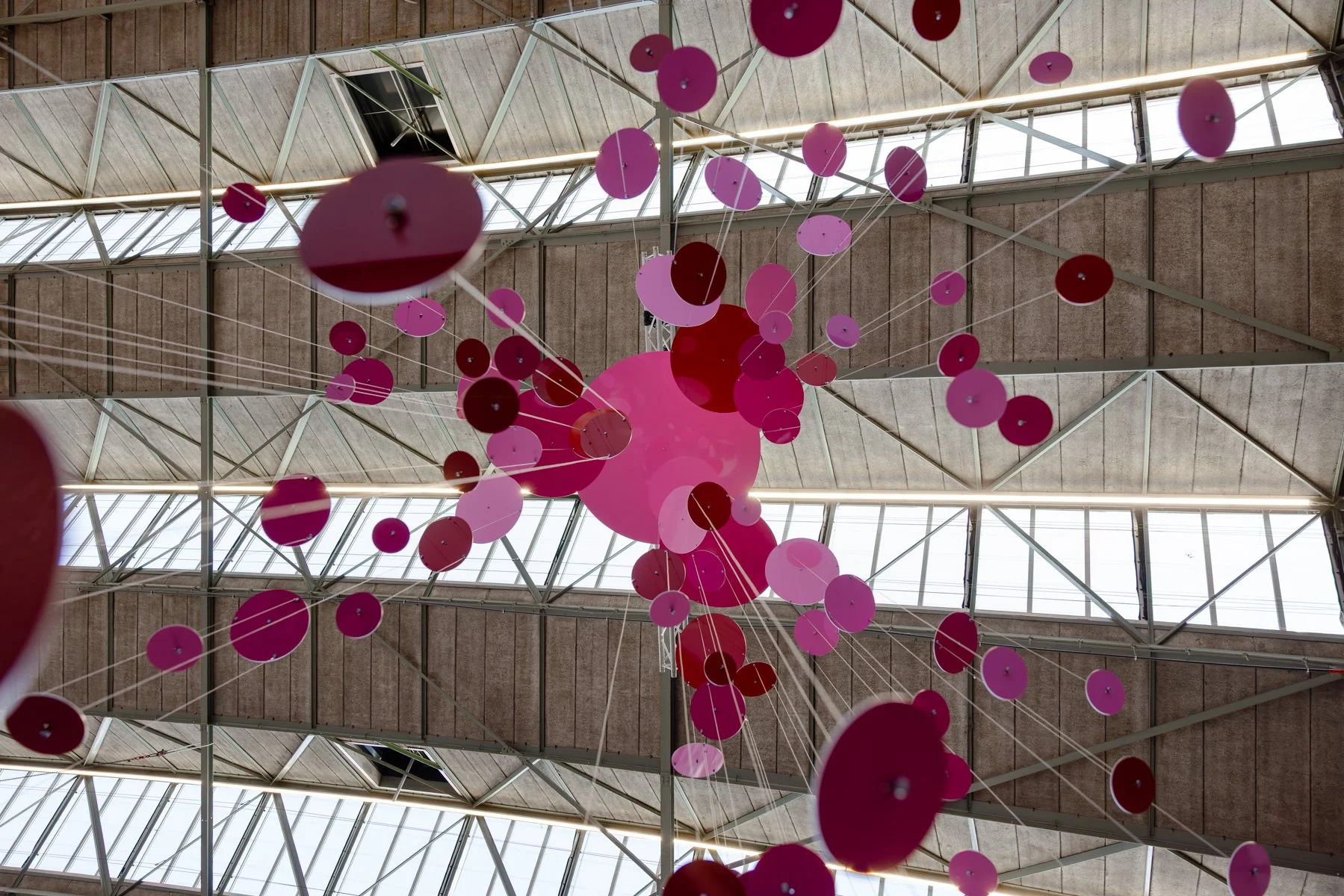 Architectural installation artwork by Freerk Wilbers featuring suspended circular forms and shifting reflections of light at an Amsterdam art fair.