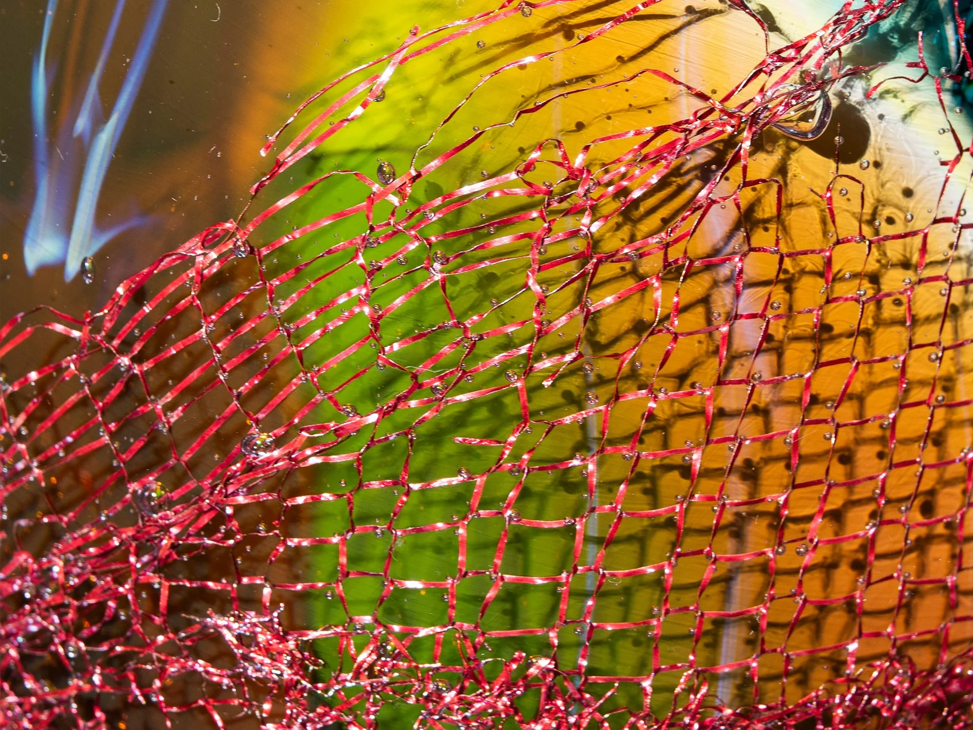 Close-up of copper cleaning sponge embedded within coloured glass by Francisca Snel