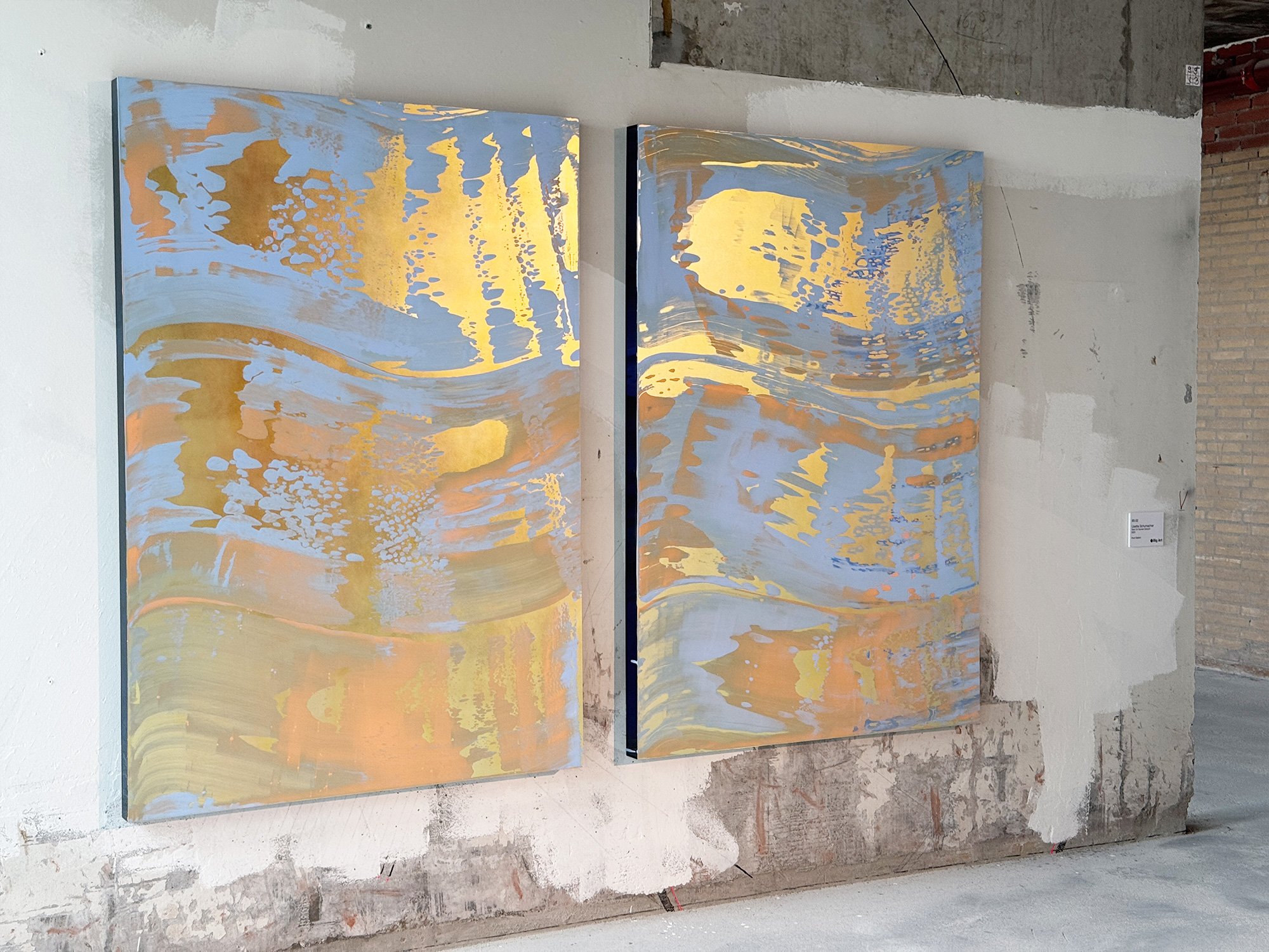 Two abstract mixed-media artworks from The View on Sunset series by Lisette Schumacher displayed side by side in an industrial exhibition space with raw walls and natural light.