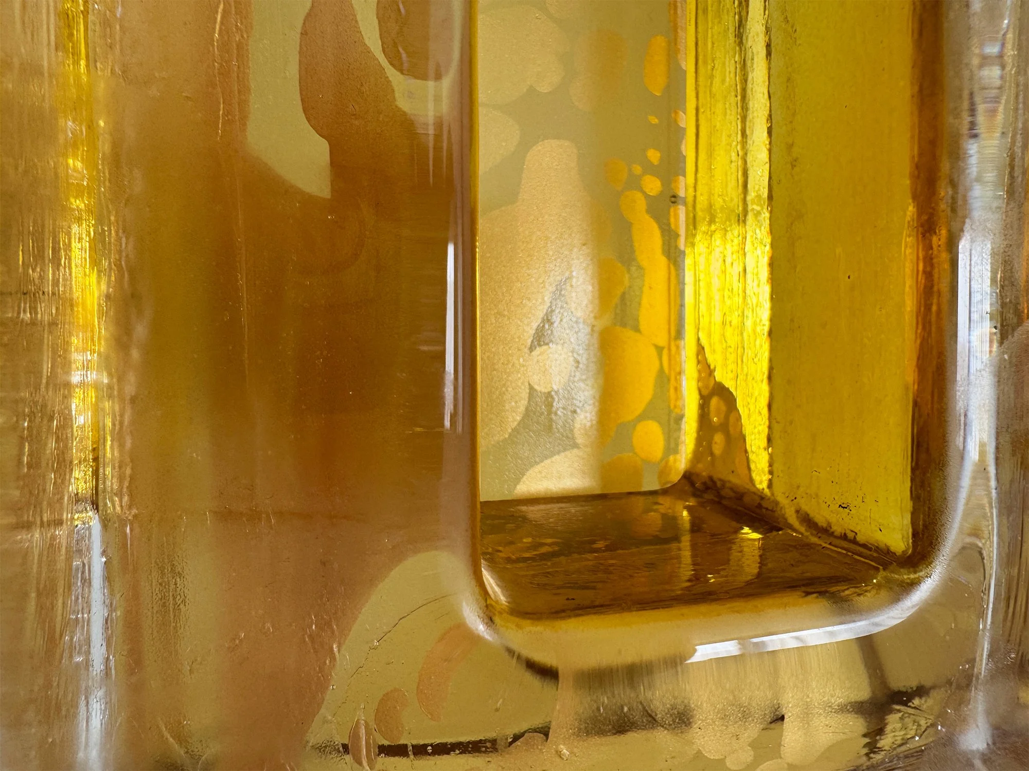 Close-up of hand-cast glass sculpture showing air bubbles and layered colour depth