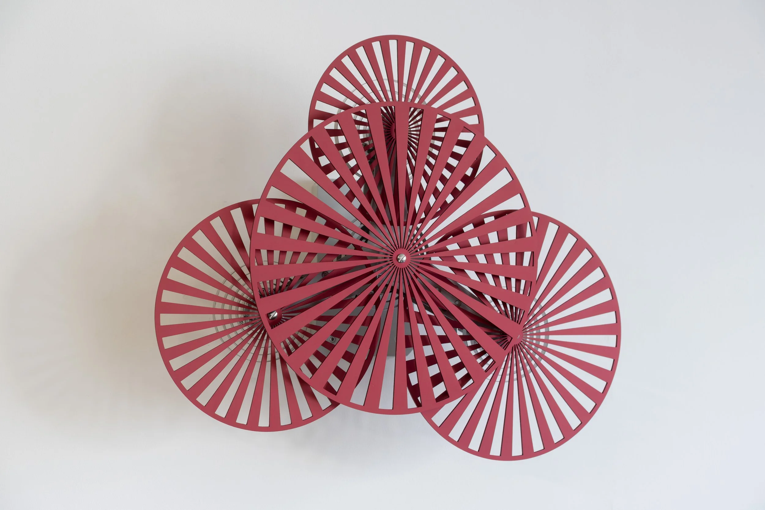 Detail view of Red Spinner by Freerk Wilbers, showing segmented circular forms, steel components and ball bearings on a white wall.