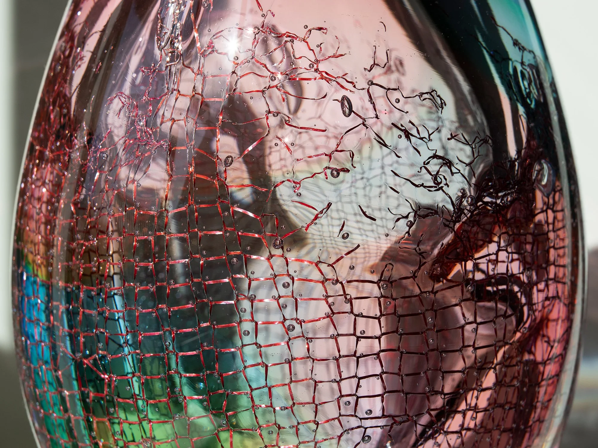 Close-up of copper cleaning sponge visible inside transparent pink glass by Francisca Snel