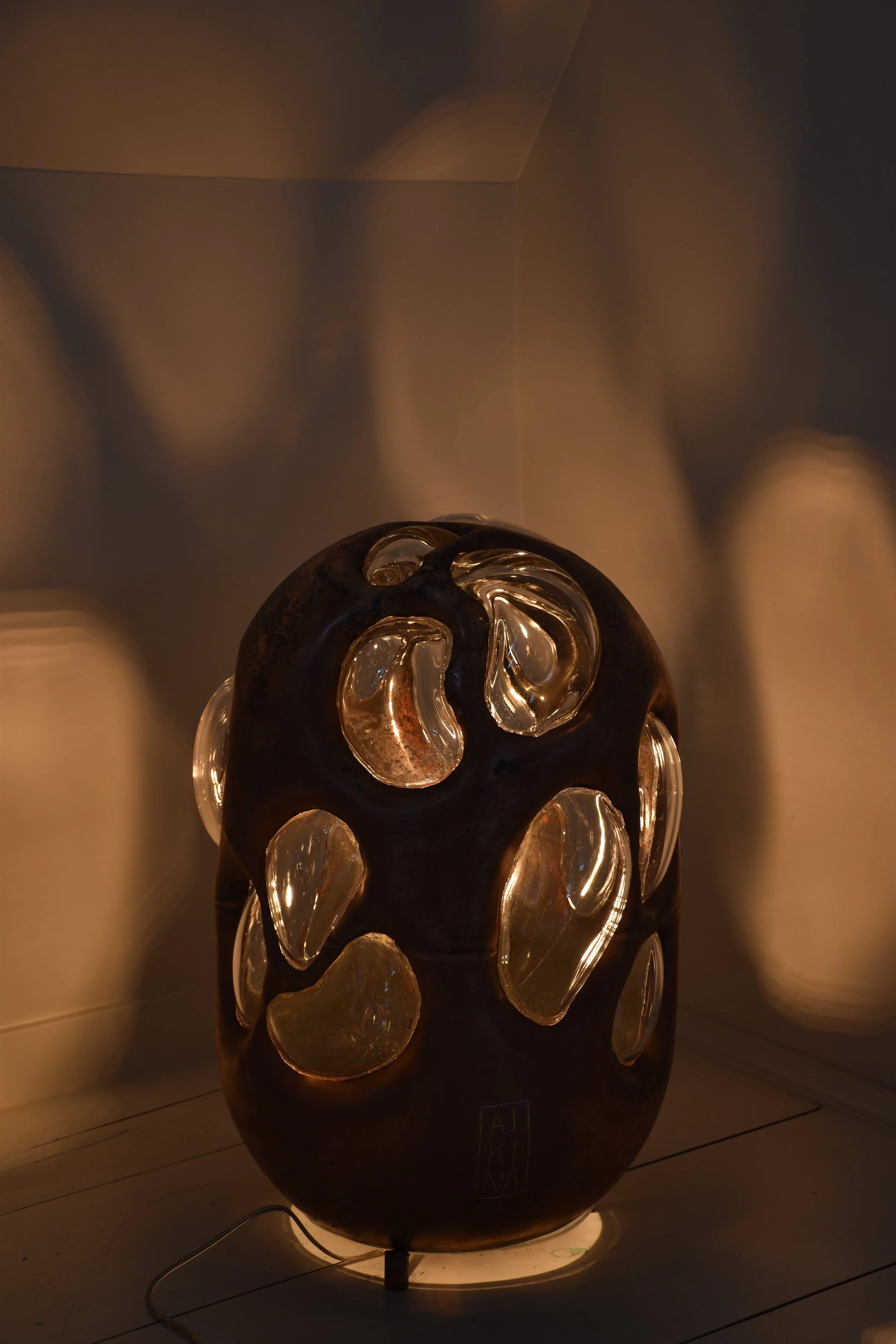 Copper and glass light sculpture by Anna Oudhof photographed in the workshop while illuminated.