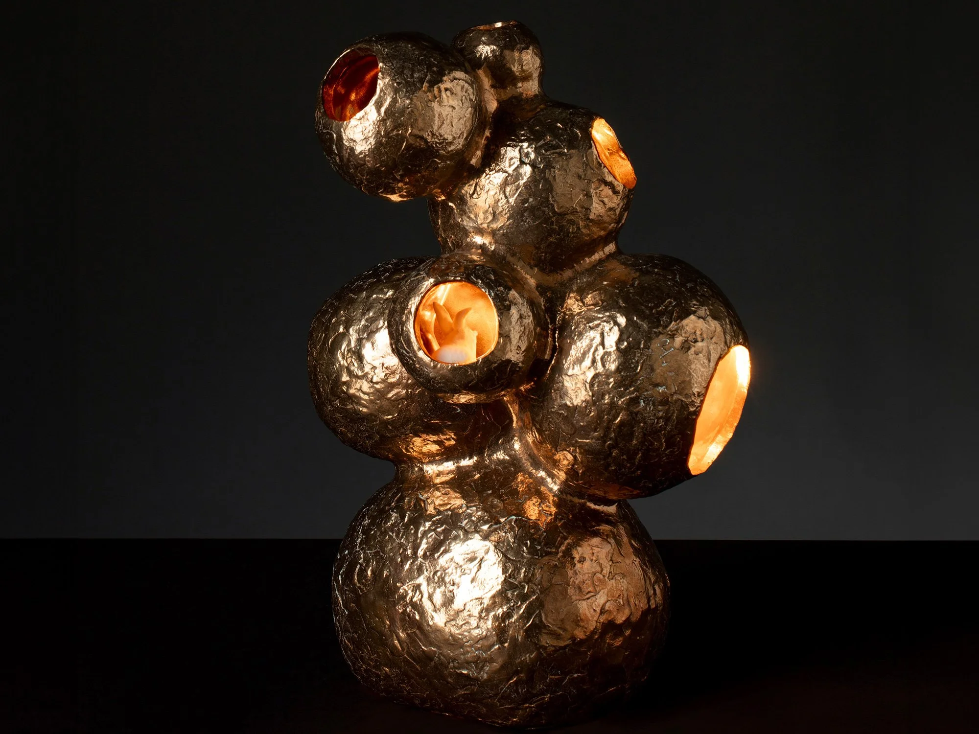 Bronze sculpture “The Rabbithole” (2021) by Jeske Haak with organic underground form and illuminated openings.
