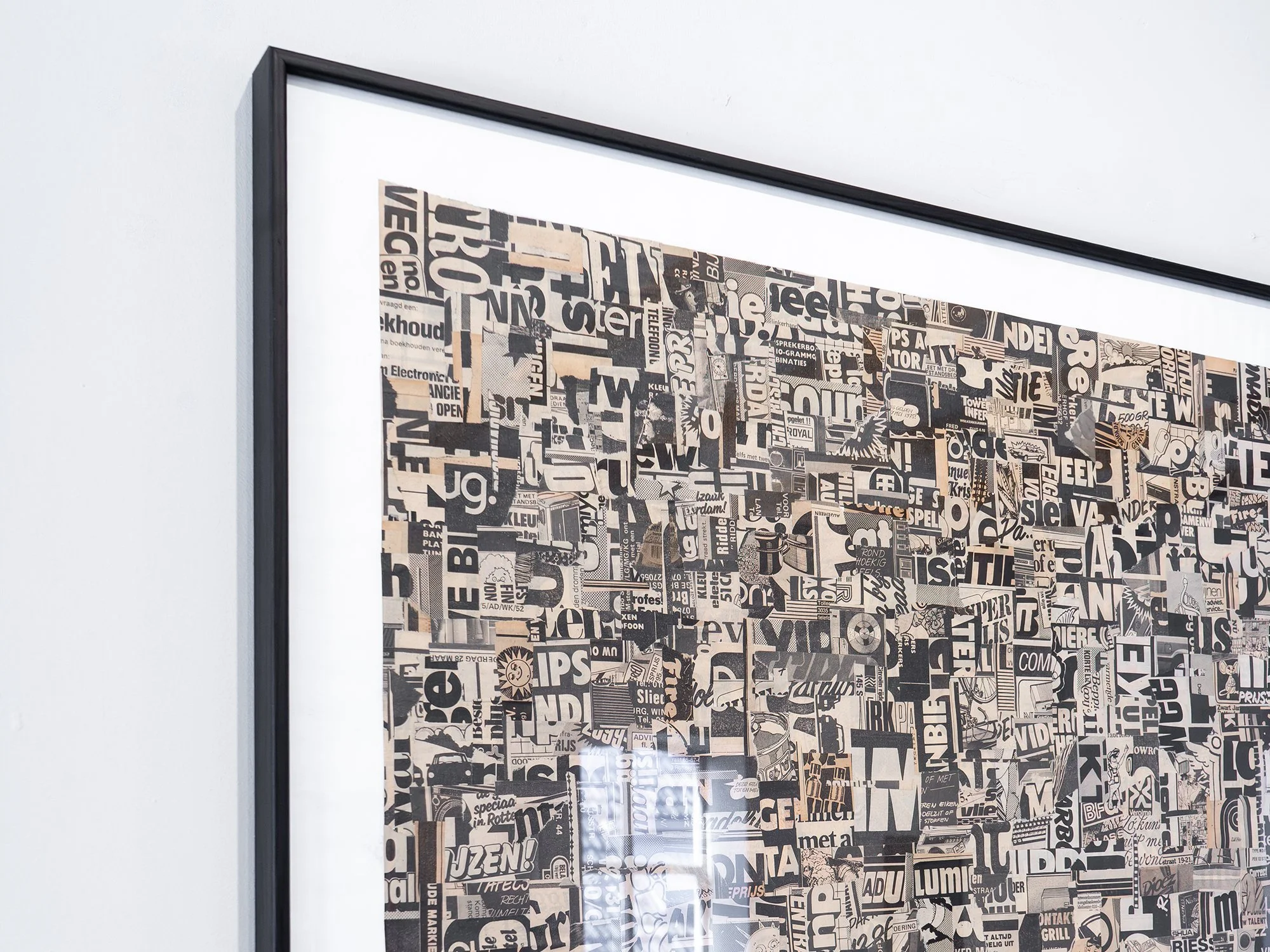 Angled view of Static001 by Saïd Kinos, with layered typography and reflections on the framed collage.