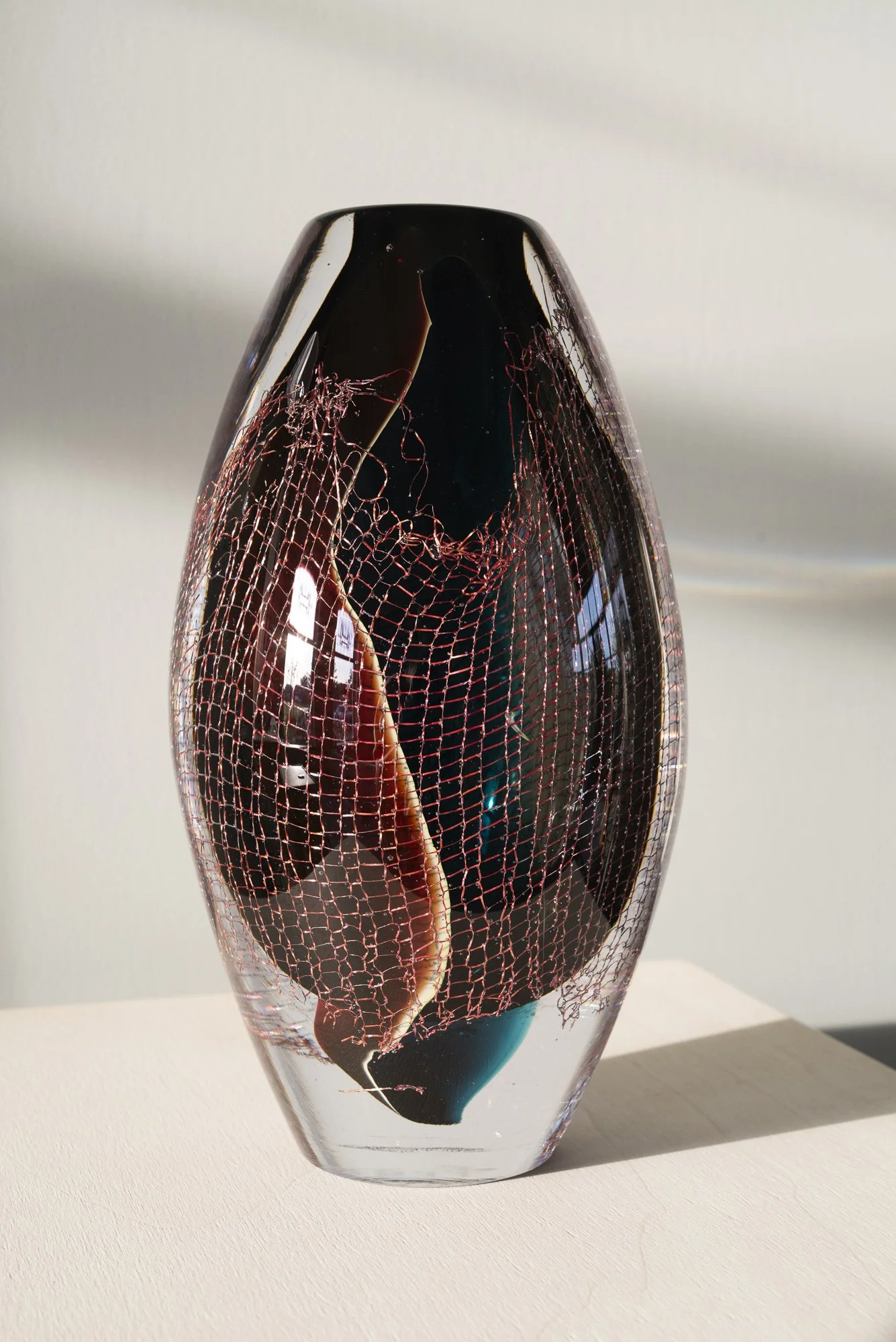 Dark glass and copper sculpture by Francisca Snel showing subtle turquoise and red colours from another angle.
