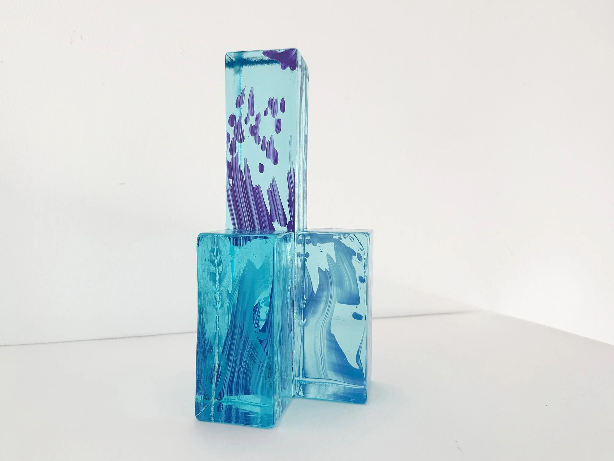 Side view of hand-cast glass object with stacked volumes and cool colour palette