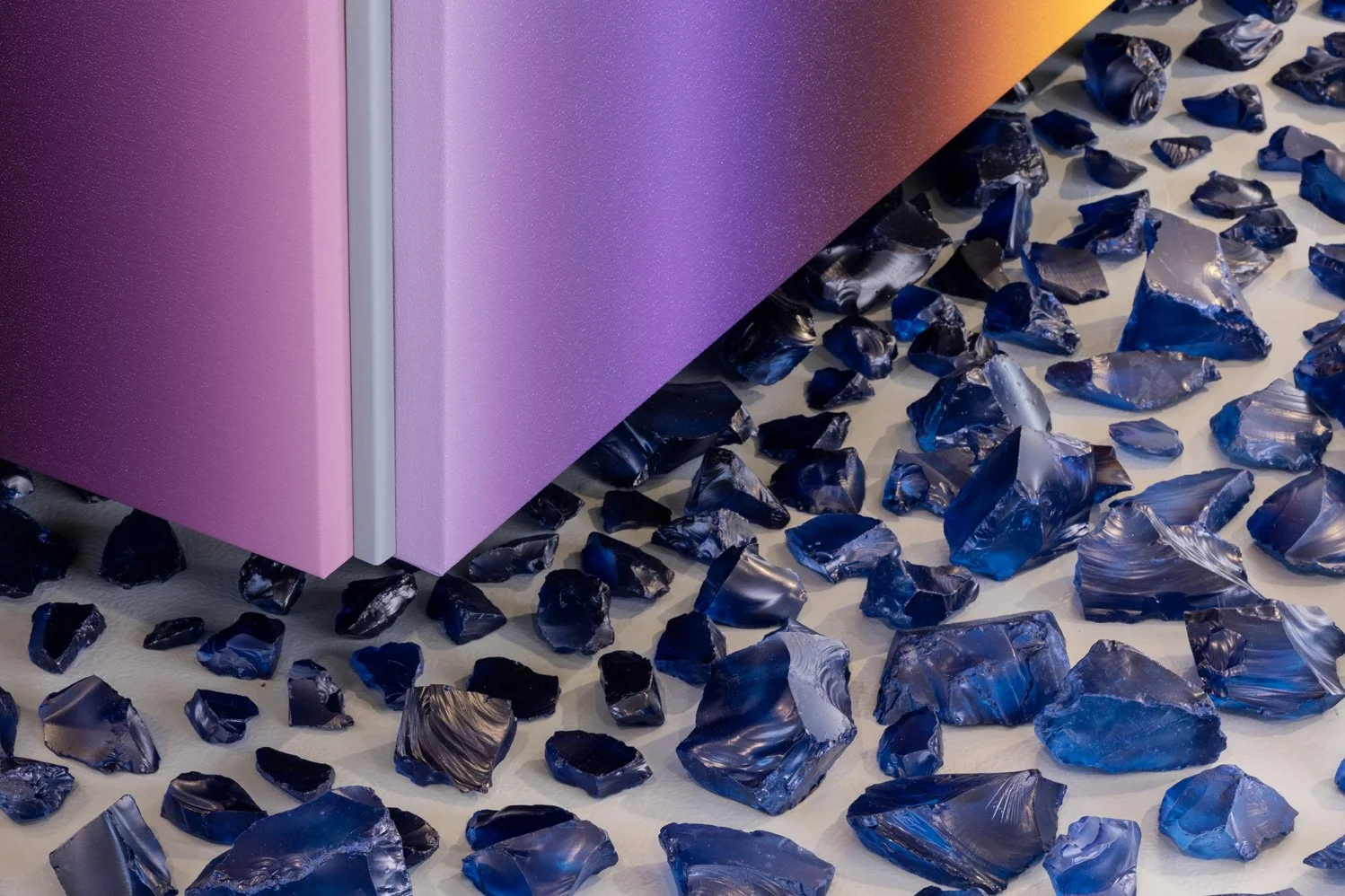 Detail of a large installation by Dutch artist Donald Schenkel, showing blue, hand-painted pieces of glass and a detail of a purple colour gradient