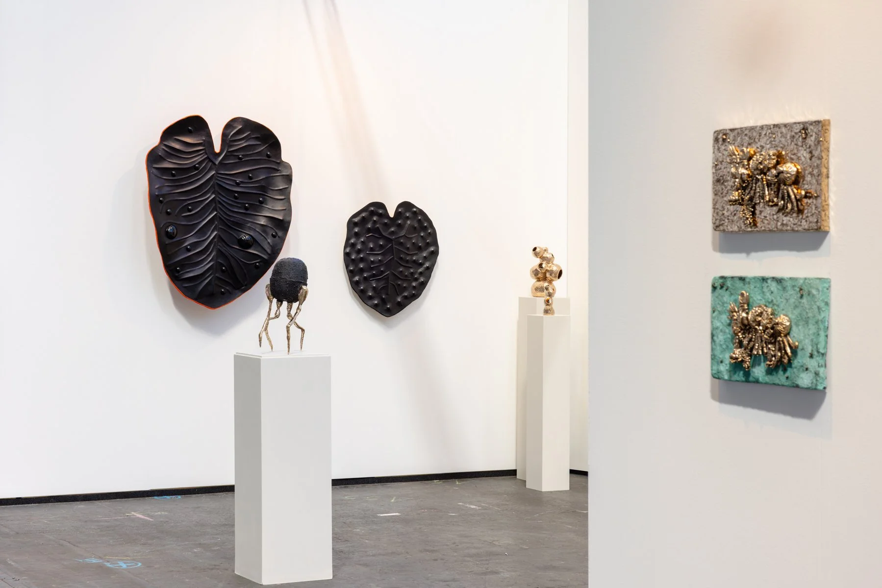 Leather and steel sculptural wall piece installed at art fair booth, clean presentation without visitors