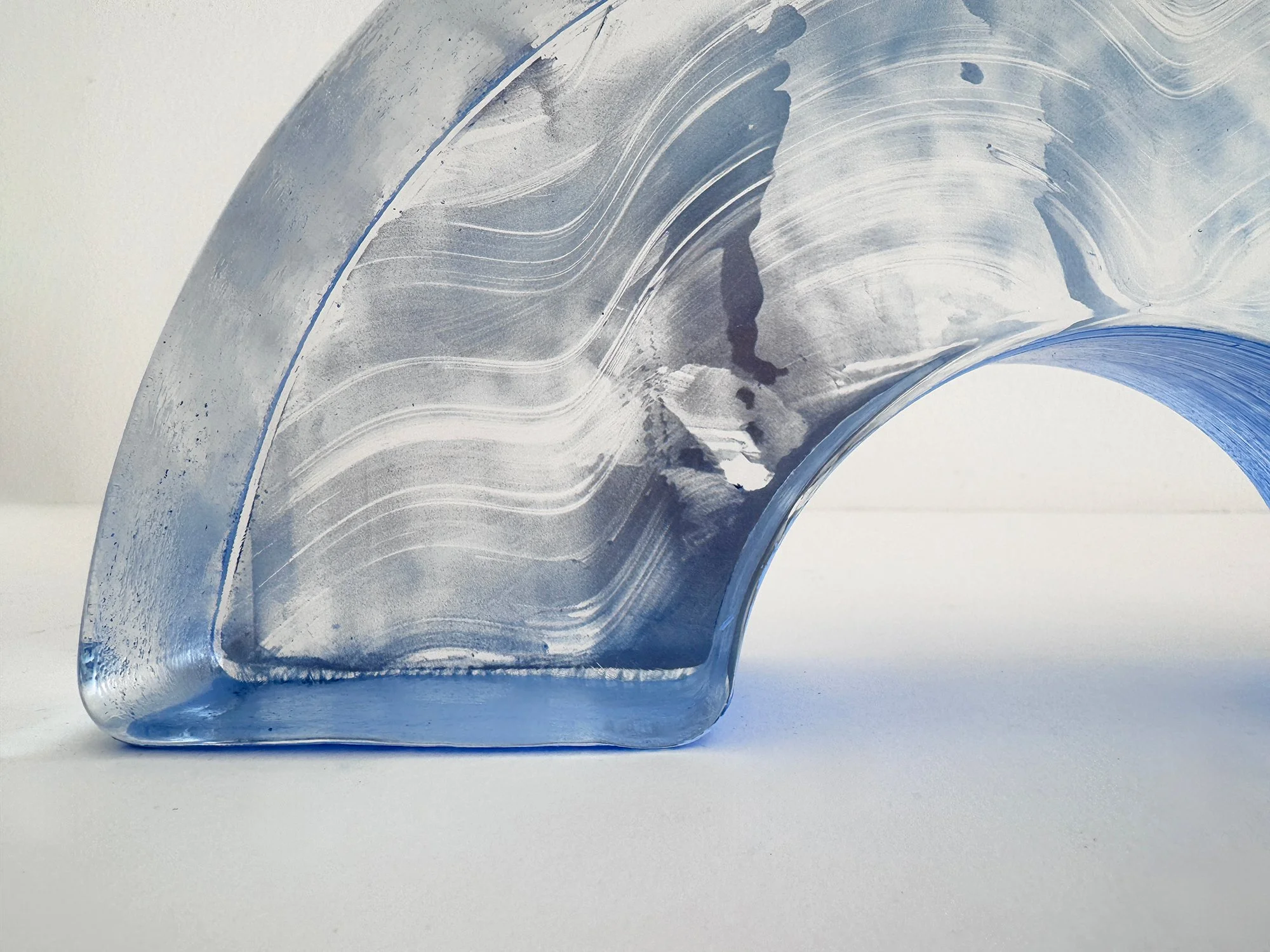 Detail of flowing white markings across the pale blue glass of Lisette Schumacher’s Spatial Shade Arch I.