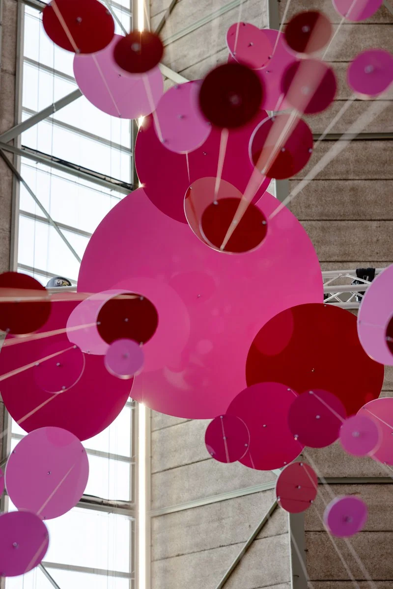 Large-scale kinetic installation Threes by Freerk Wilbers shown at an art fair in Amsterdam, with reflective circular elements moving subtly through space.