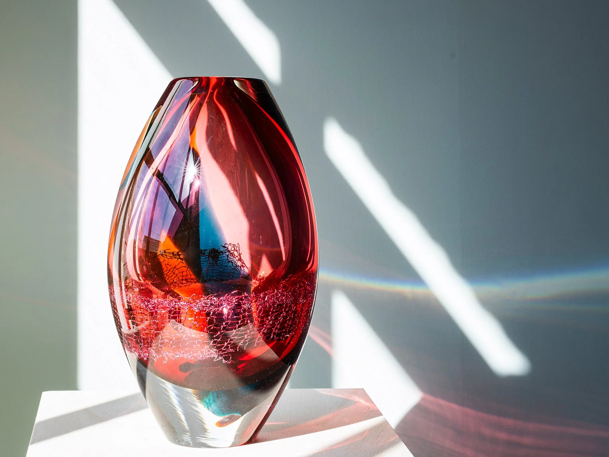 Warm-coloured glass and copper sculpture by Francisca Snel with red, amber and orange tones in sunlight
