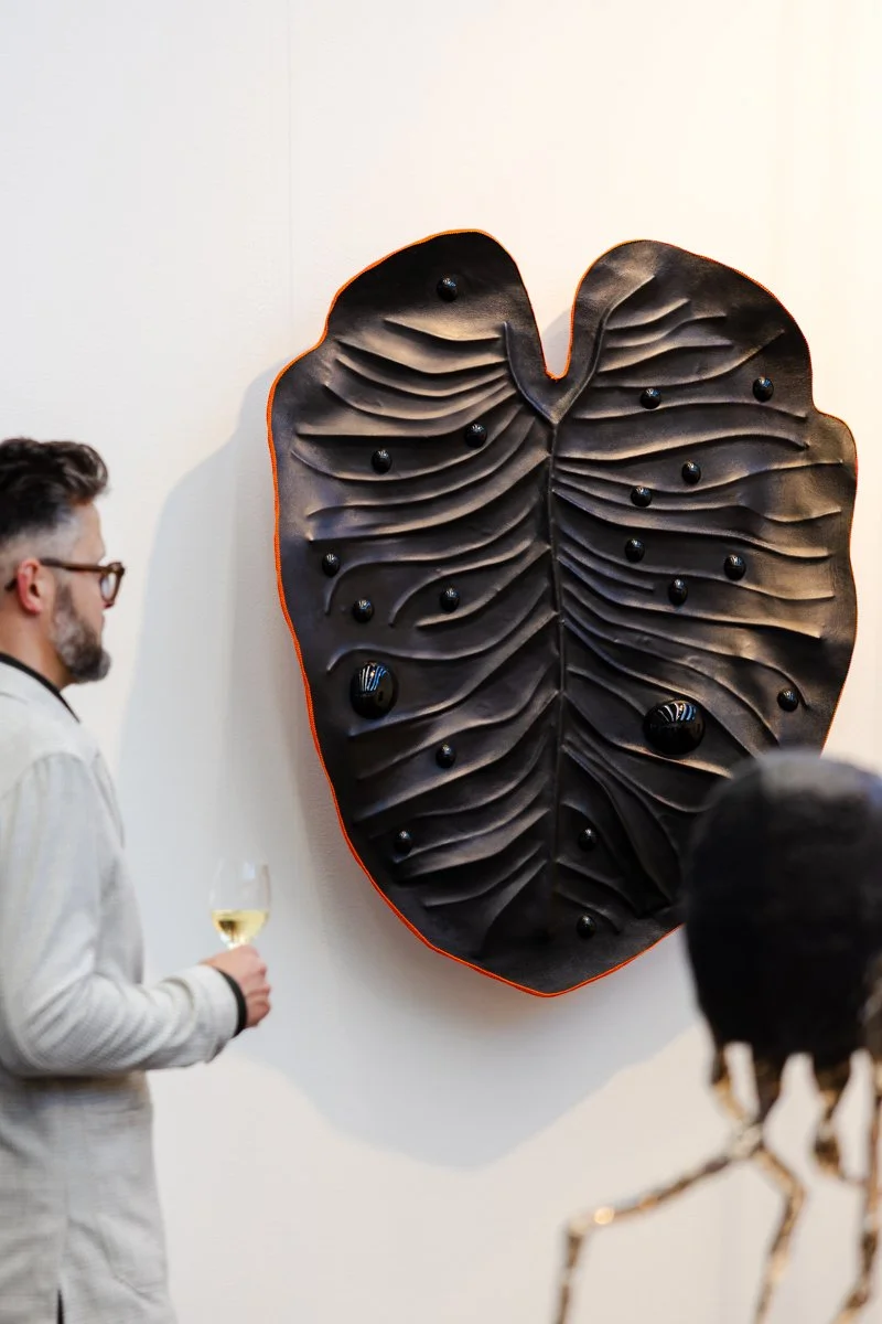 Leather and steel sculptural wall work by Madelon Uljee with visitor viewing the piece at KunstRAI, showing scale and presence in the space