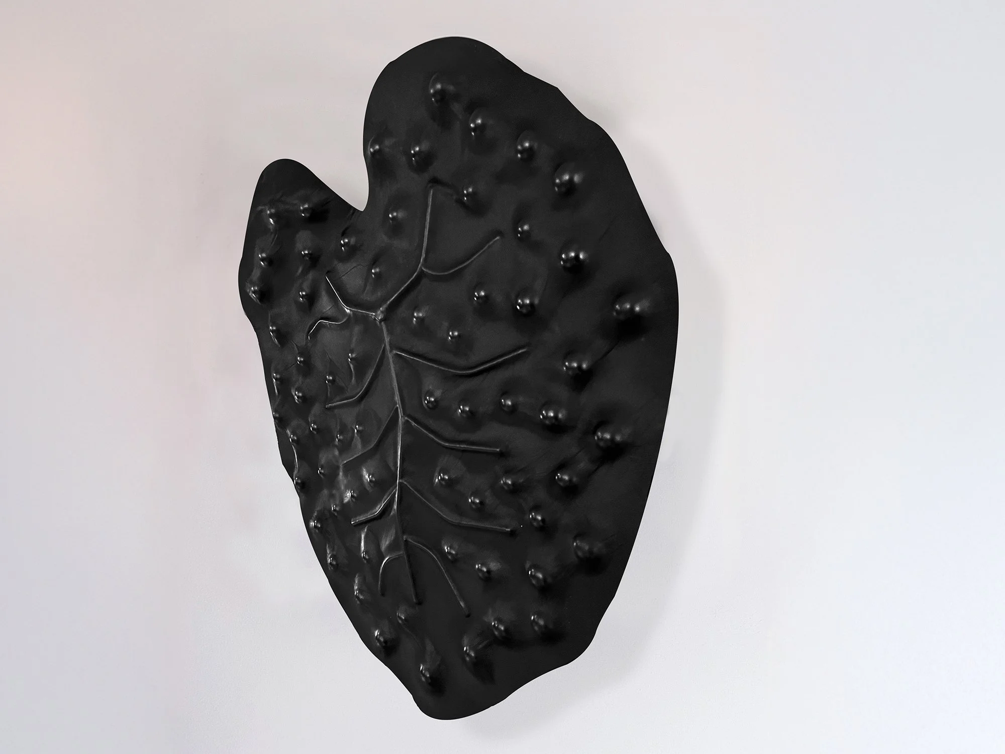 Contemporary leather wall relief showing biomorphic form with central vein and textured surface